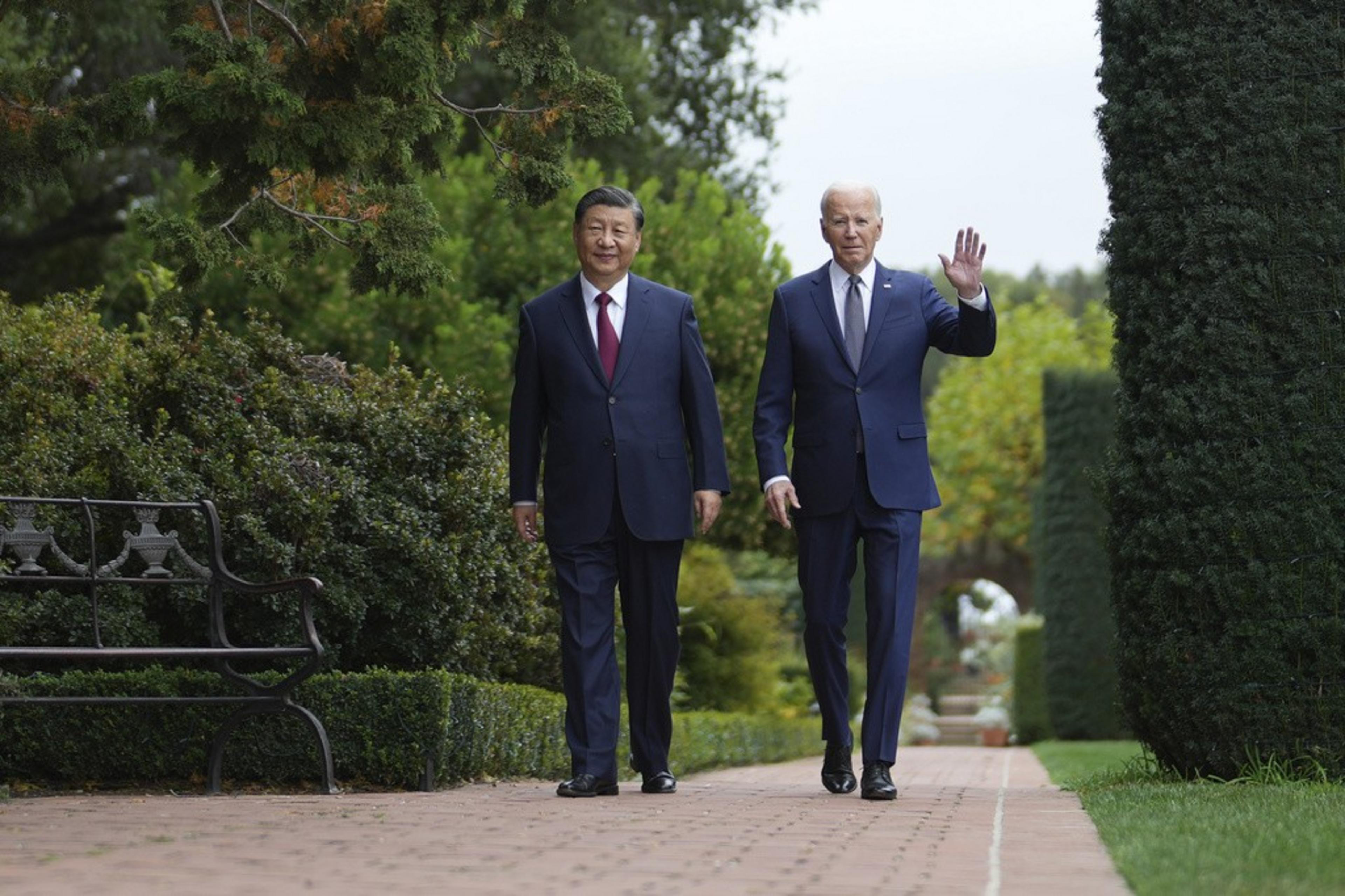 Two men in suits, Xi Jinping and Joe Biden, walk through a garden