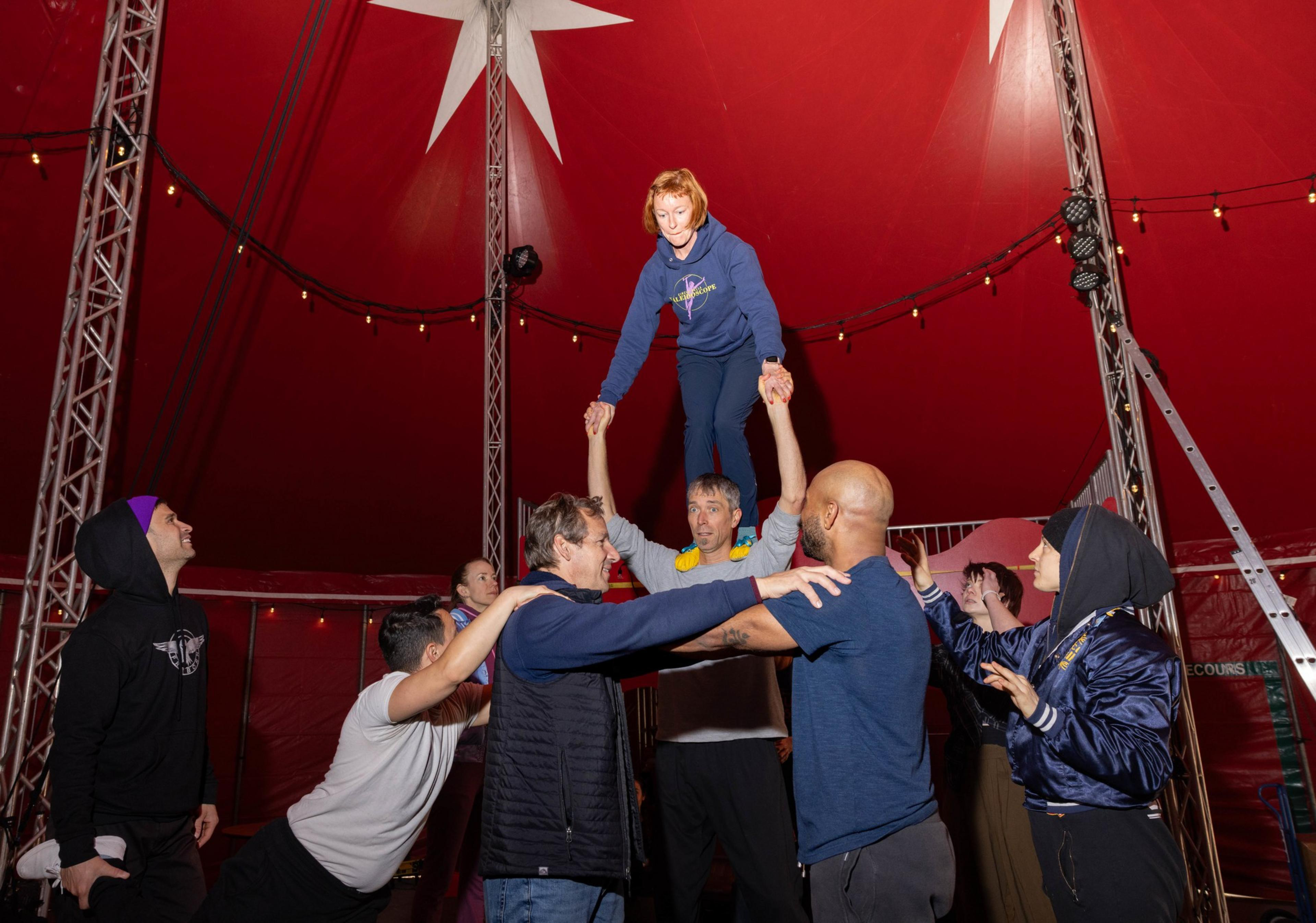 A group of people crate a human platform for a person to stand on.