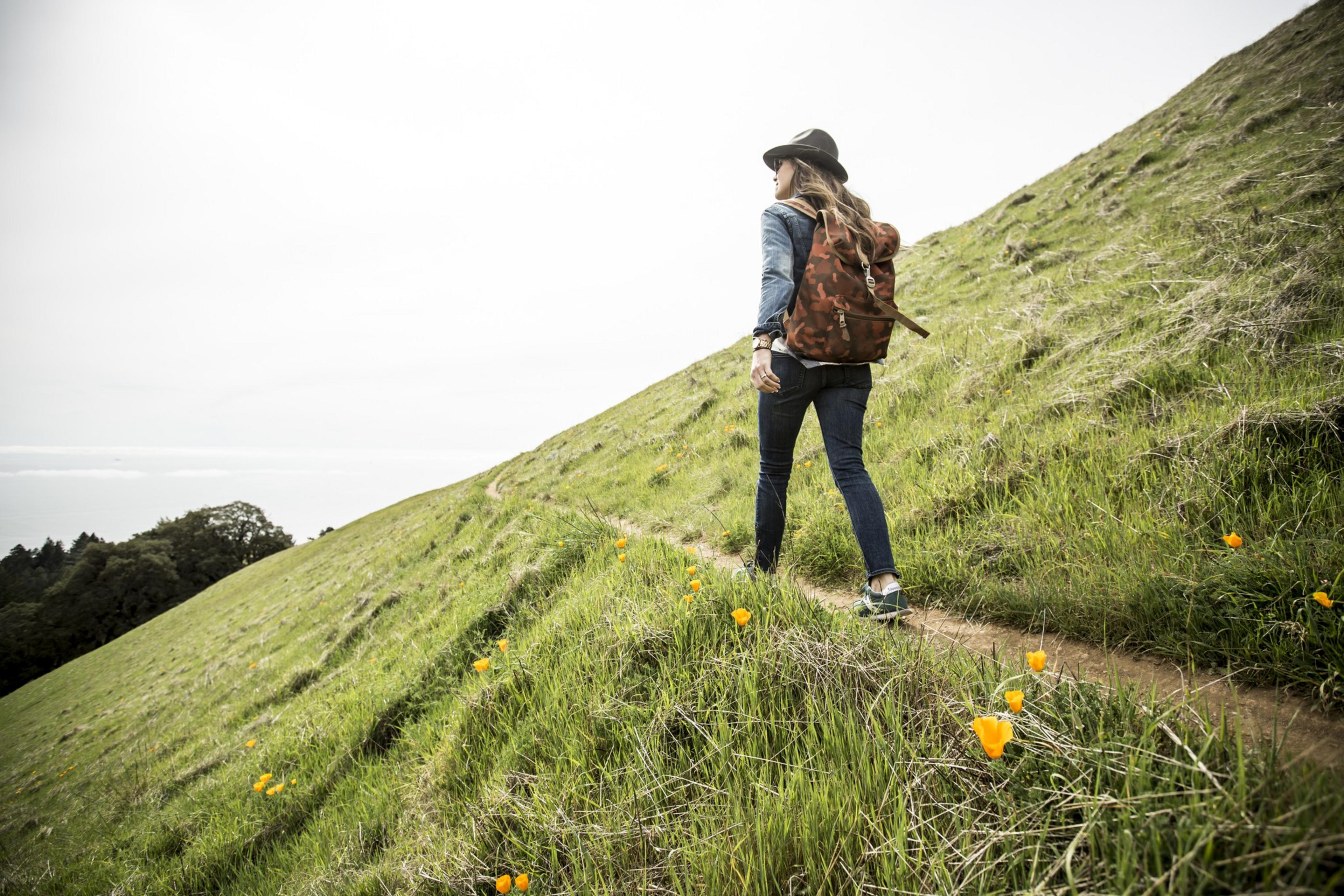 A person with a backpack hikes a trail along a mountain.