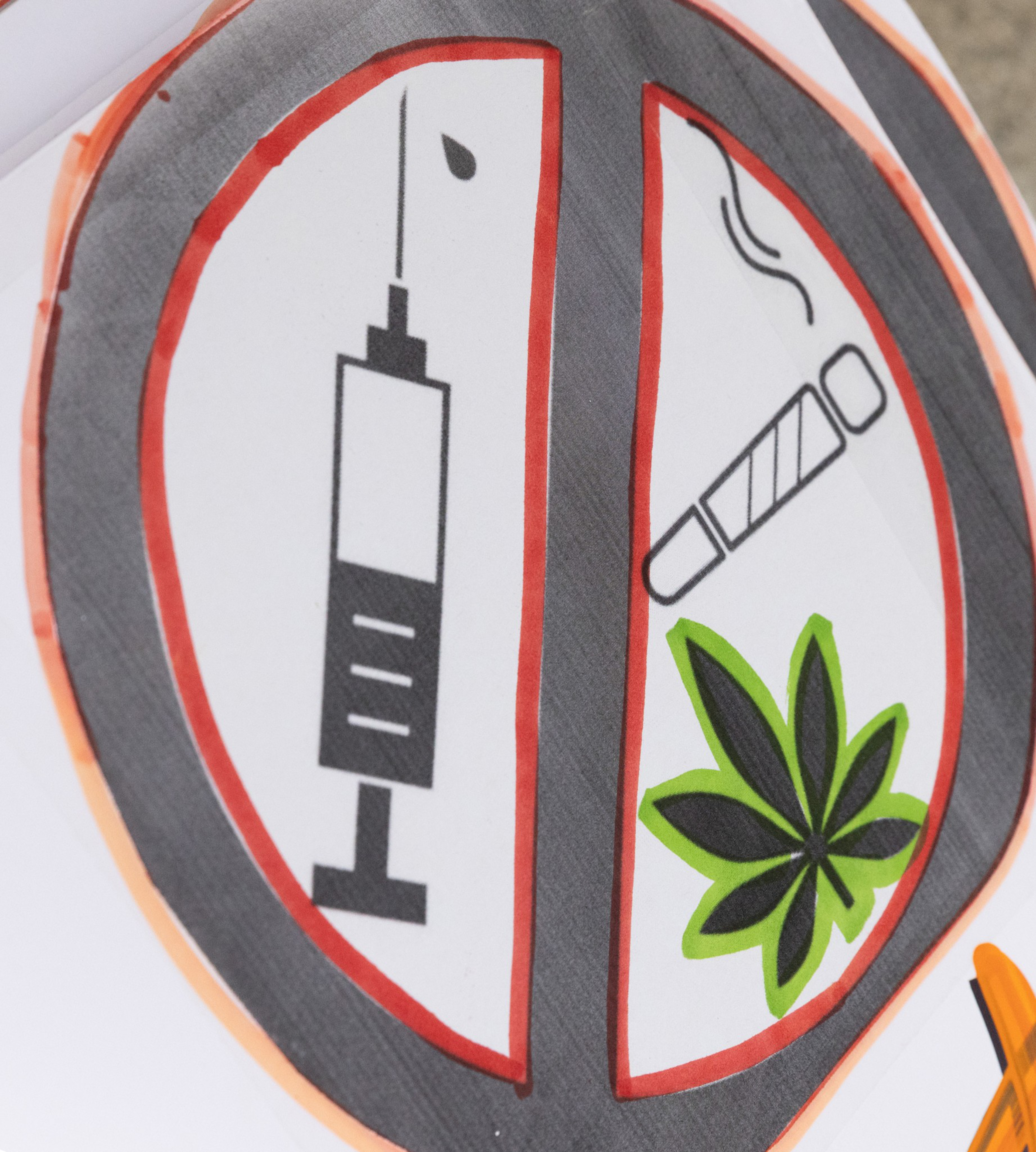 A circle divided by a vertical line contains a syringe on the left and a smoking cigarette with a cannabis leaf on the right.