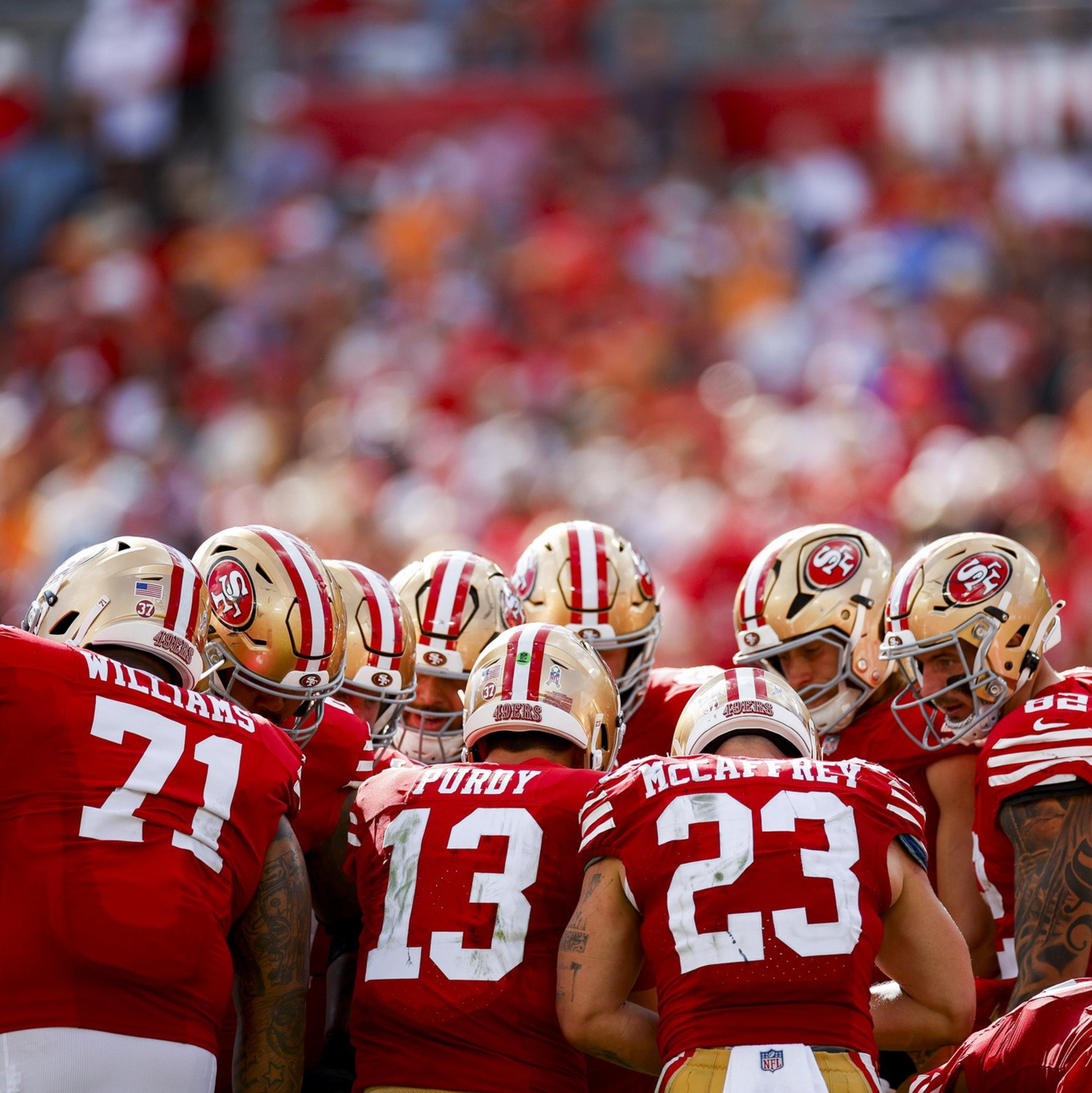 A photo of men wearing red outfits standing in a huddle.
