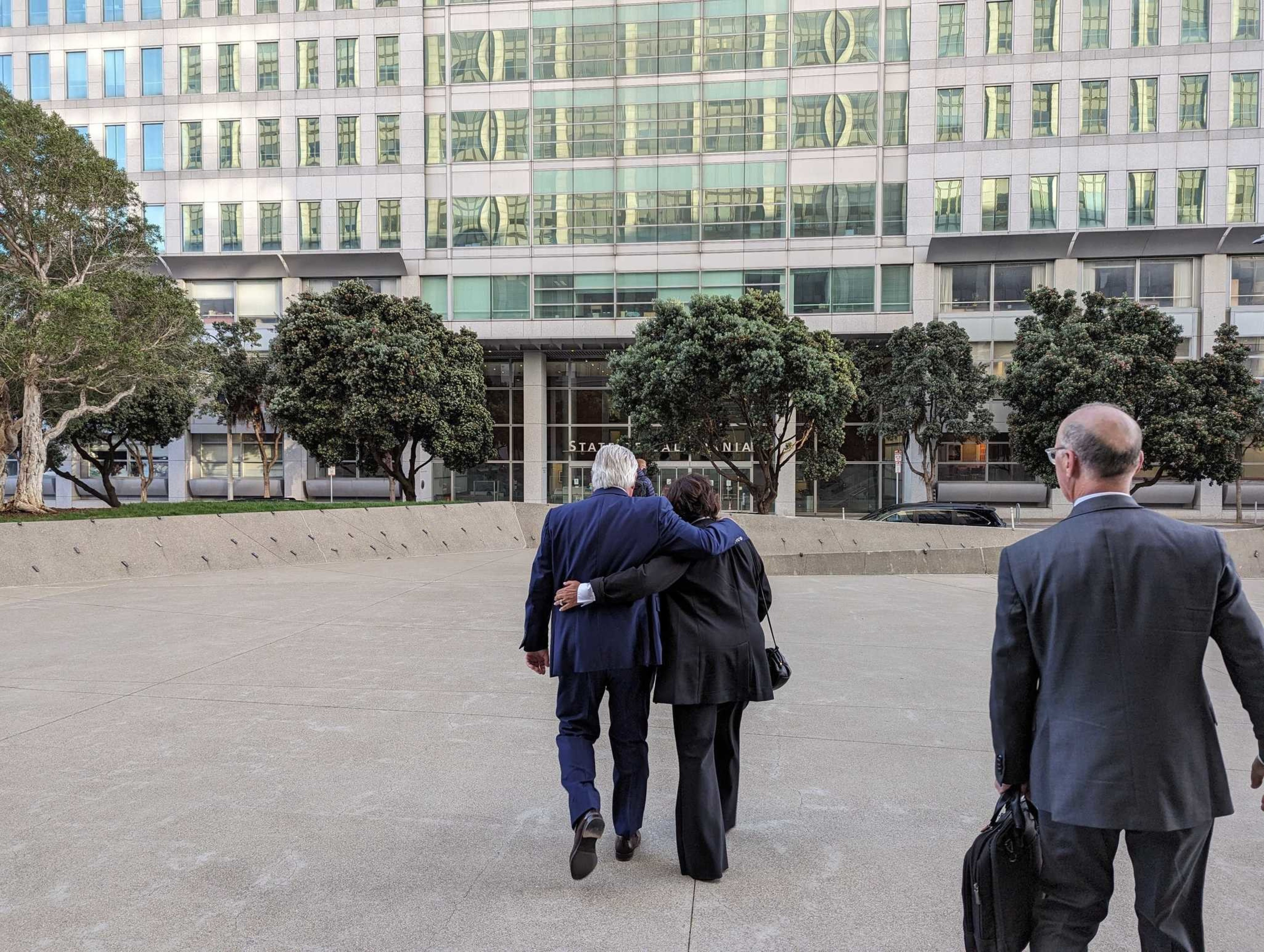 A man walks away from the camera arm-in-arm with a woman.