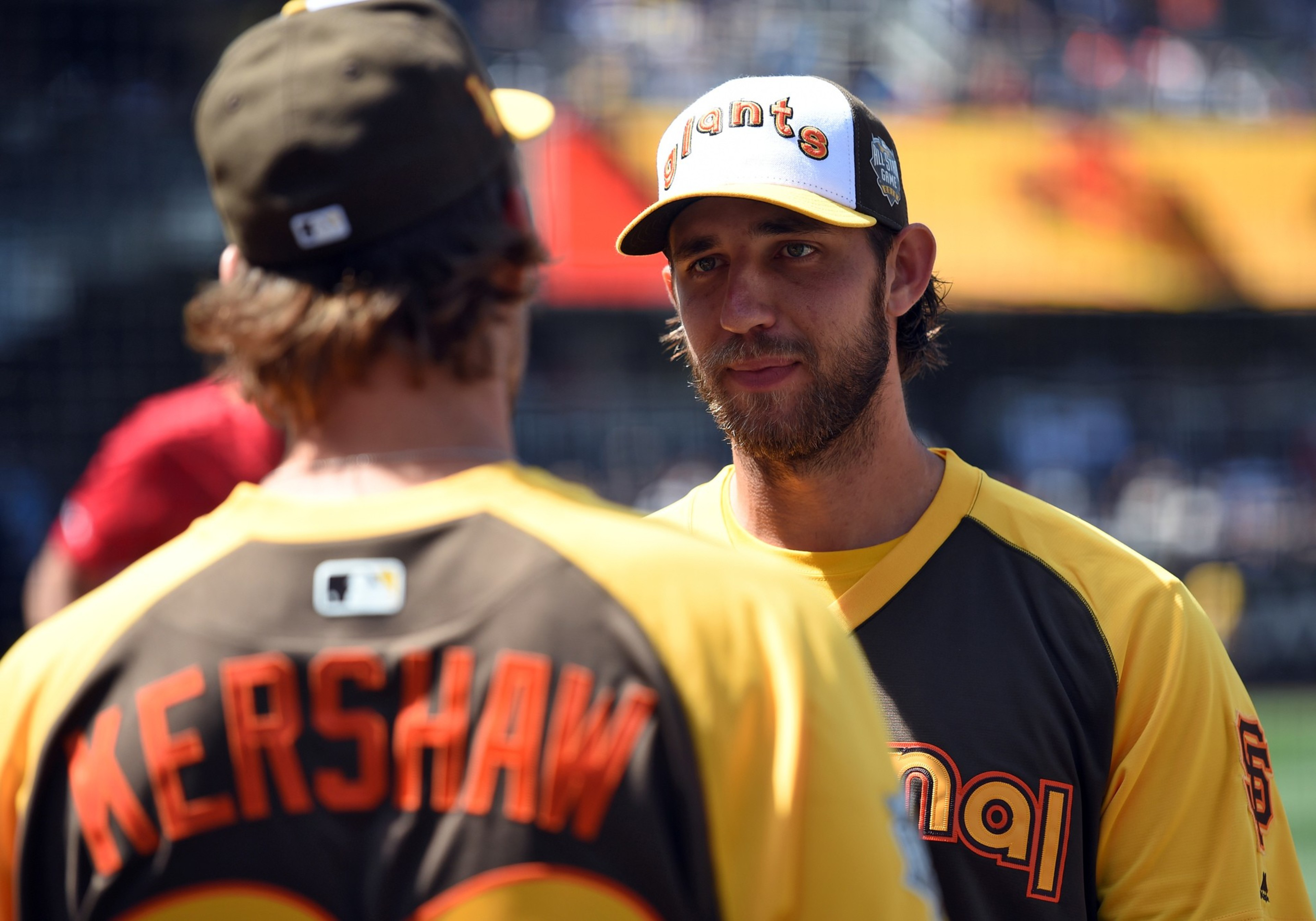 A man in a yellow and black Giants baseball jersey and cap looks intently at another man wearing a jersey with "Kershaw" on the back.