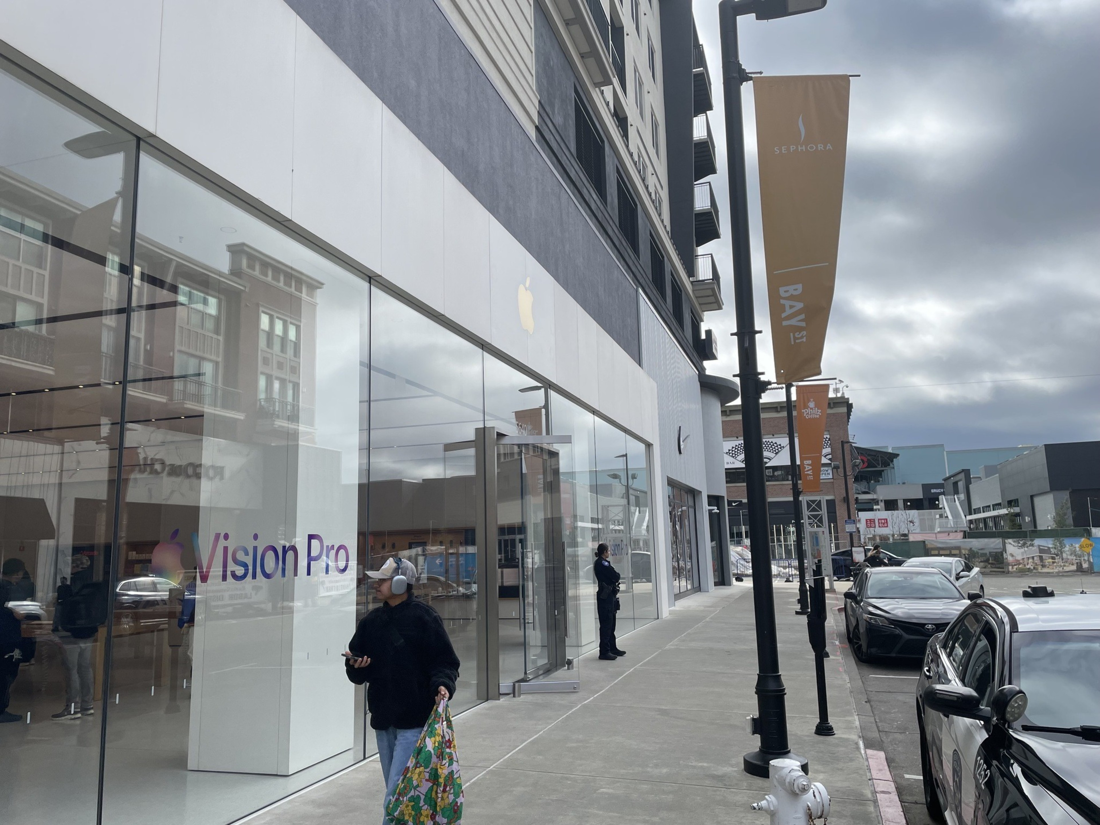 A person holding a shopping bag walks past an Apple store.