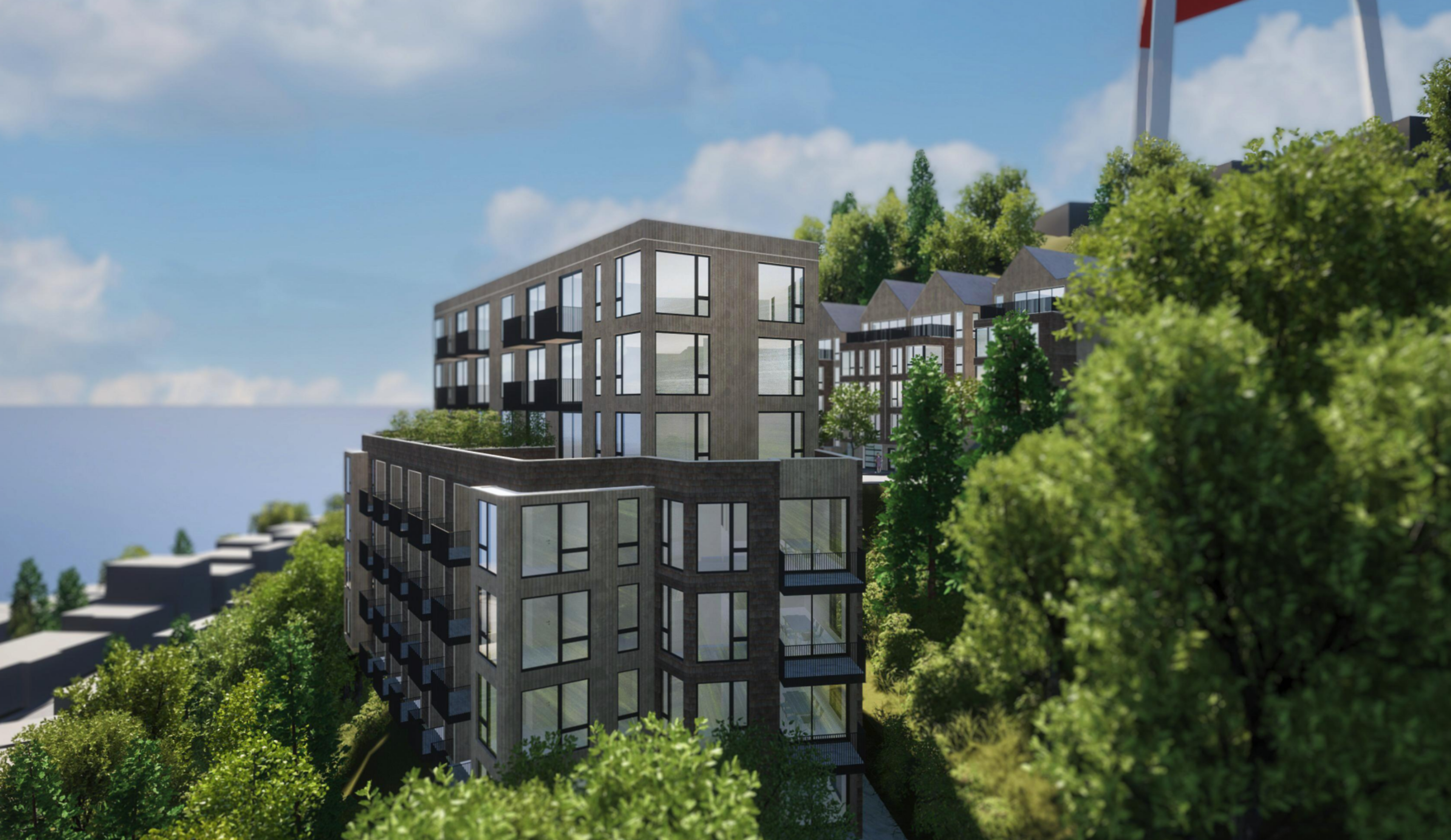 Modern multi-story residential buildings stand amidst lush green trees on a hillside under a partly cloudy sky.