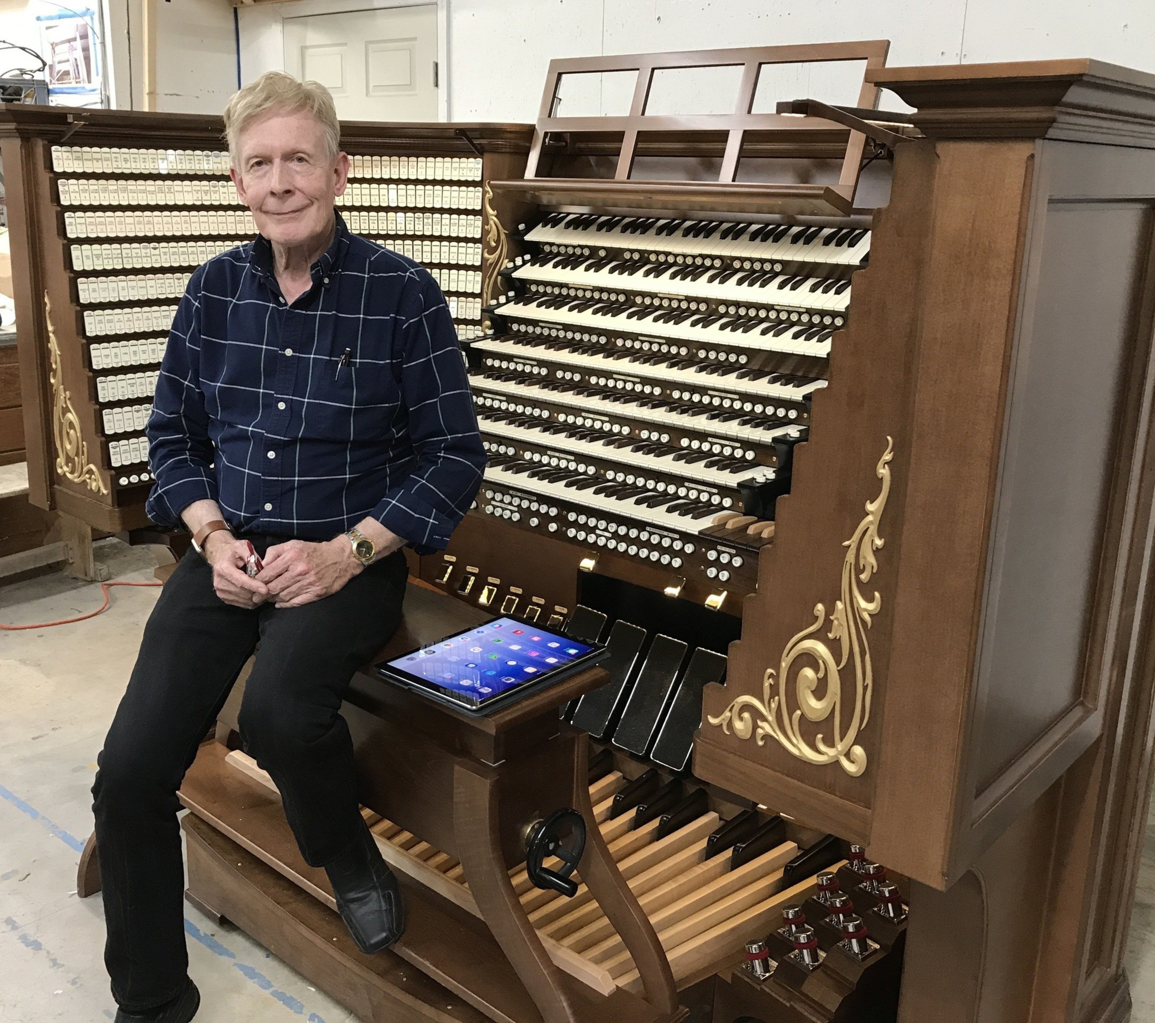 A man stands beside an organ with an iPad.