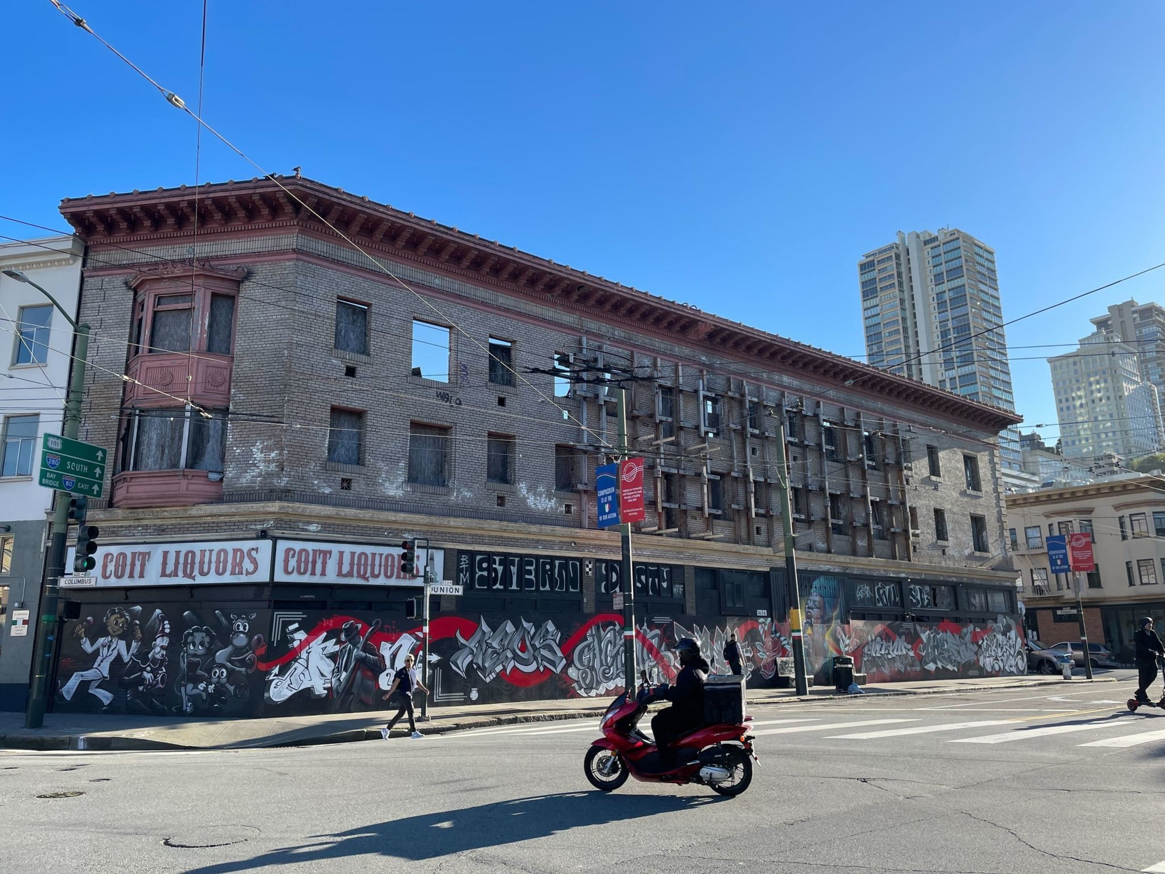 A scooter drives past an empty brick building.