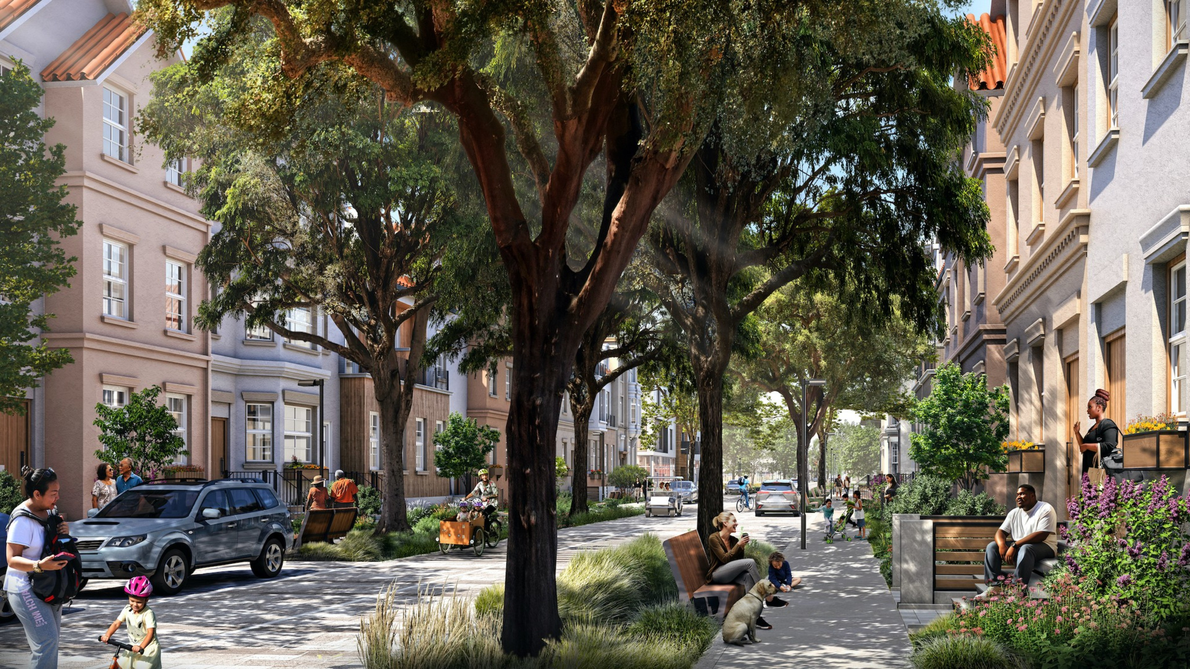 A sunny, lively street lined with trees and historic-style buildings, as people walk, sit, and drive cars.