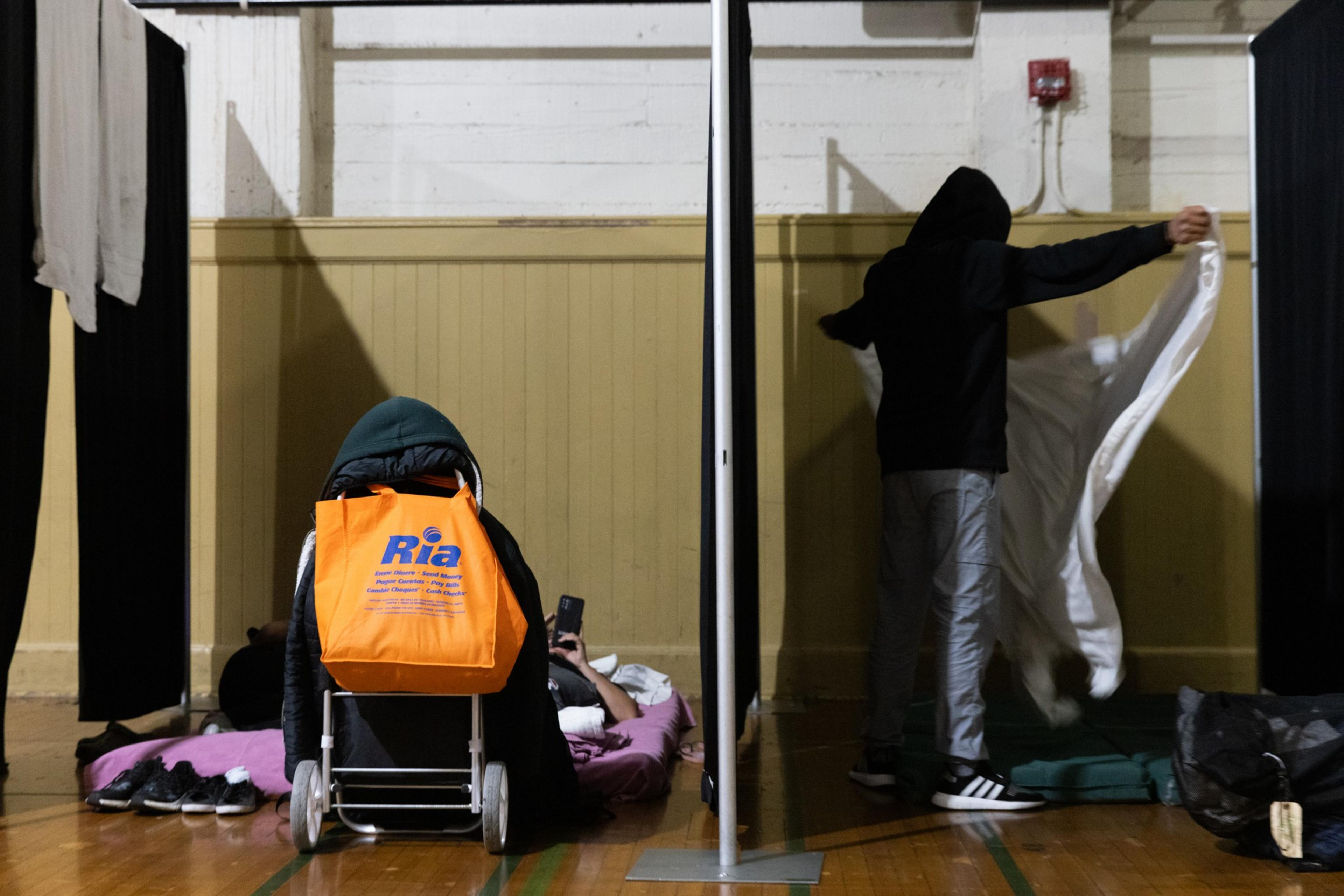 Two sleeping areas in a school gymnasium separated by a single curtain.