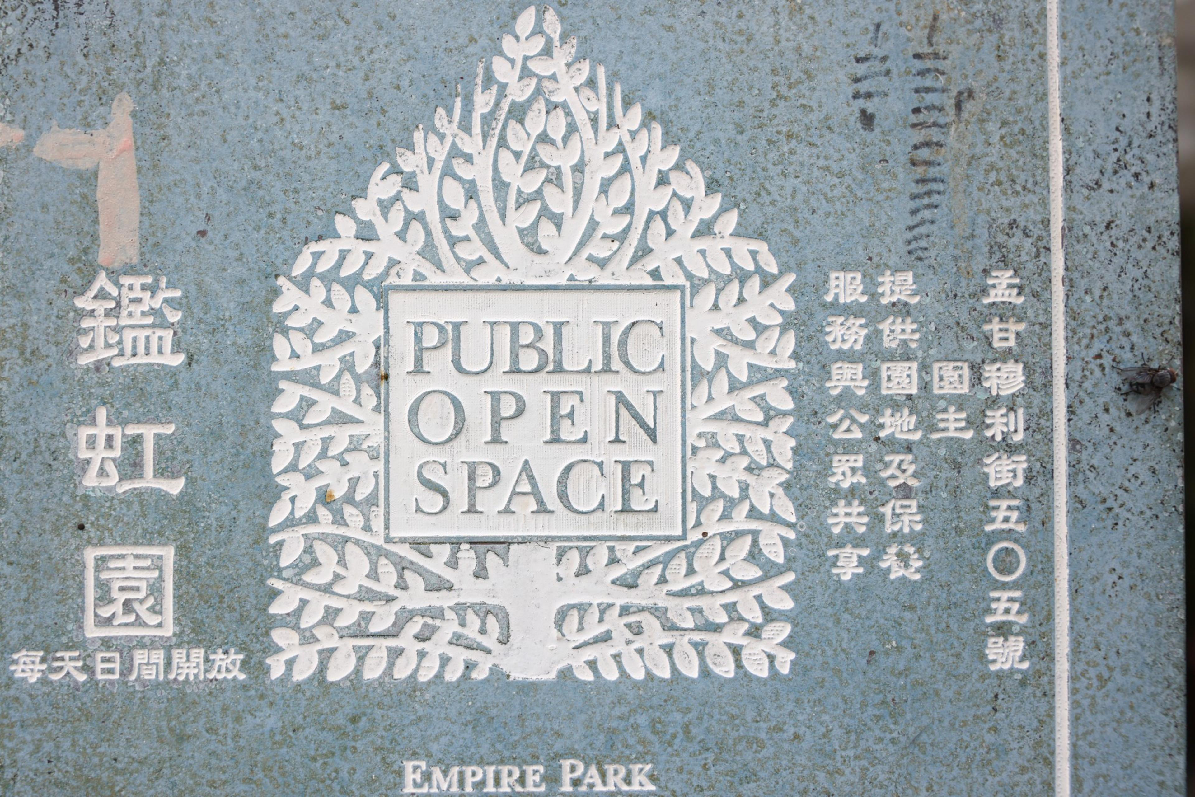 A gray plaque with a decorative tree design contains the text "PUBLIC OPEN SPACE" and Chinese characters, with "EMPIRE PARK" at the bottom.