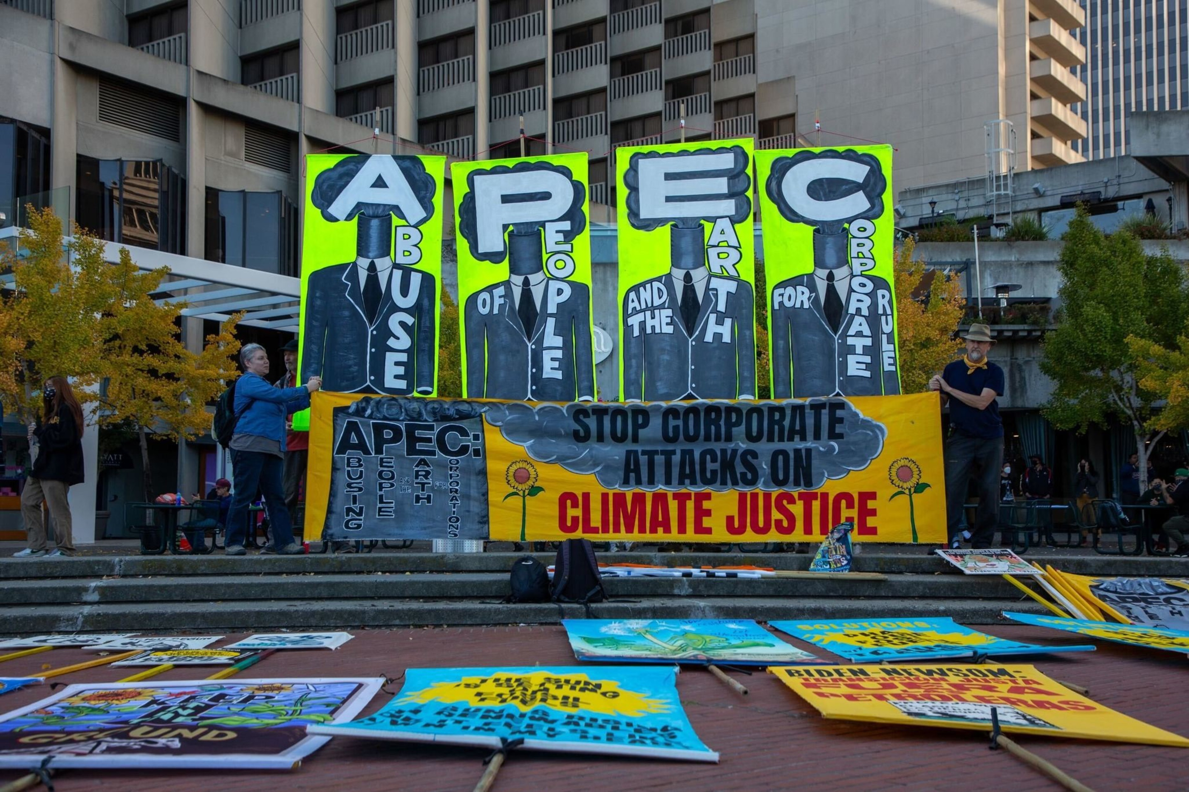 A bright yellow sign spelling out APEC is posted in a plaza.