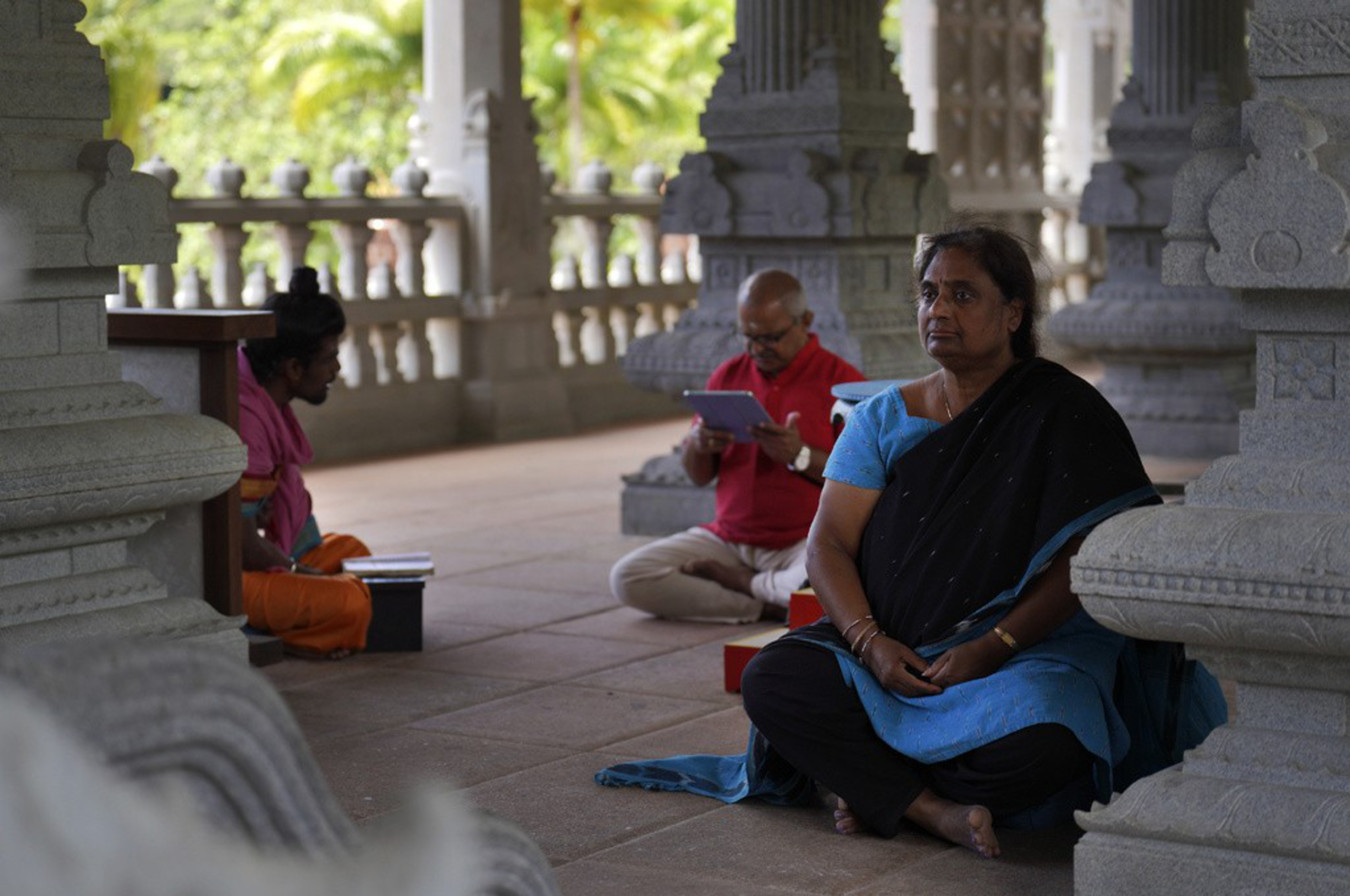 People sit cross-legged on a veranda. 