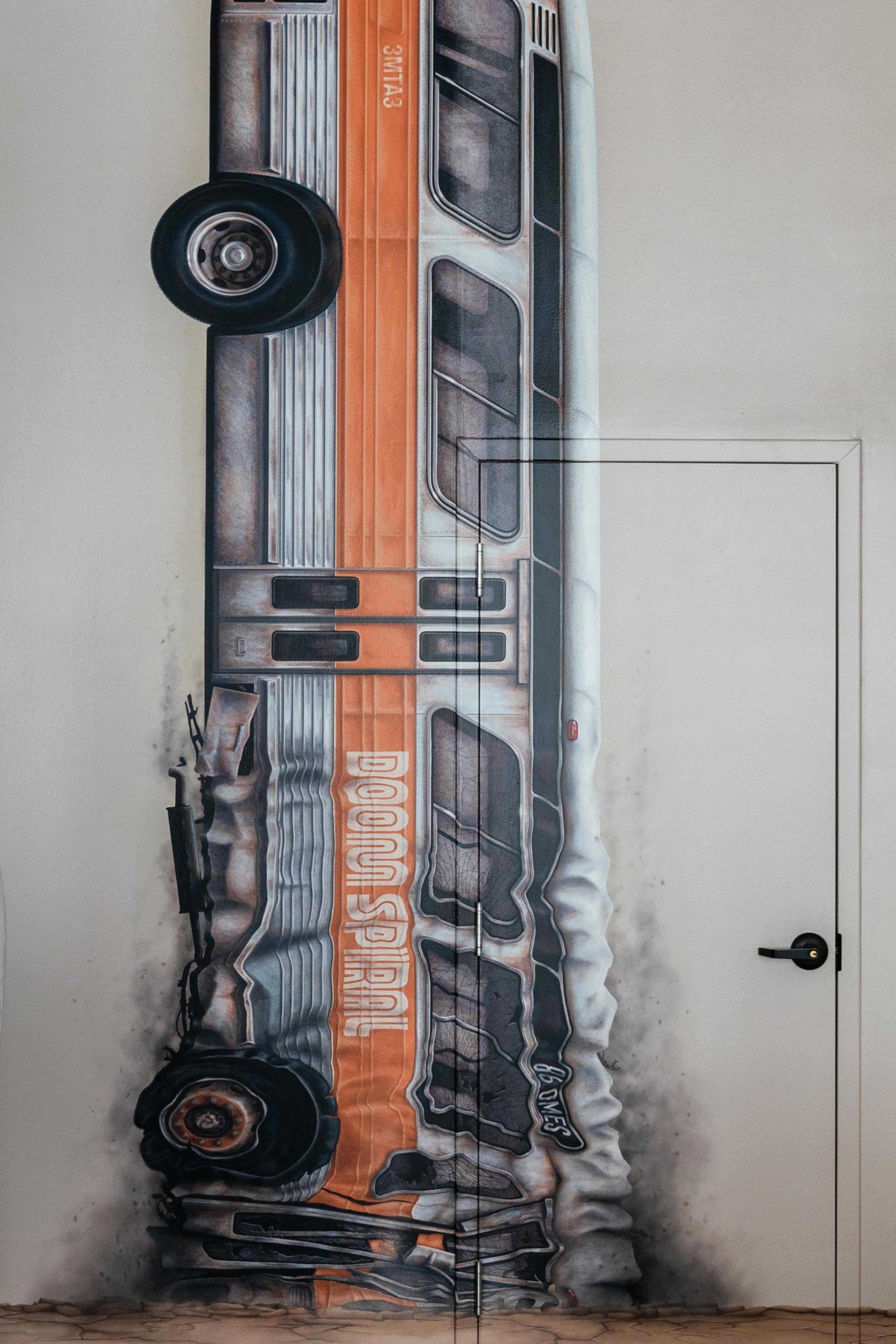 A wall mural depicting a detailed, rusted orange and gray bus, vertically positioned, with the words &quot;DOOM SPIRAL&quot; on its side, intricately painted over a door.