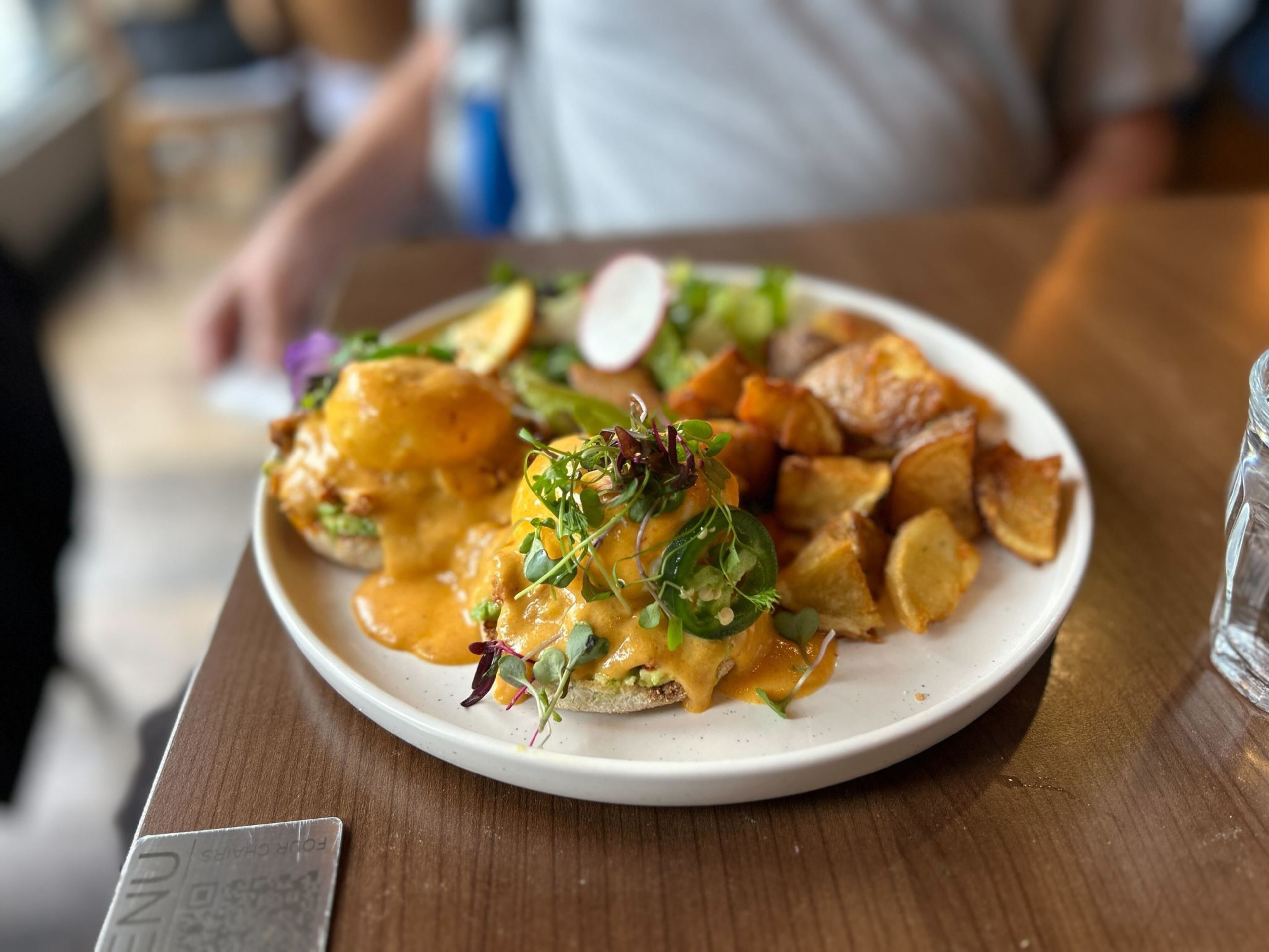 a plate of chipotle benedict with salad and home fries