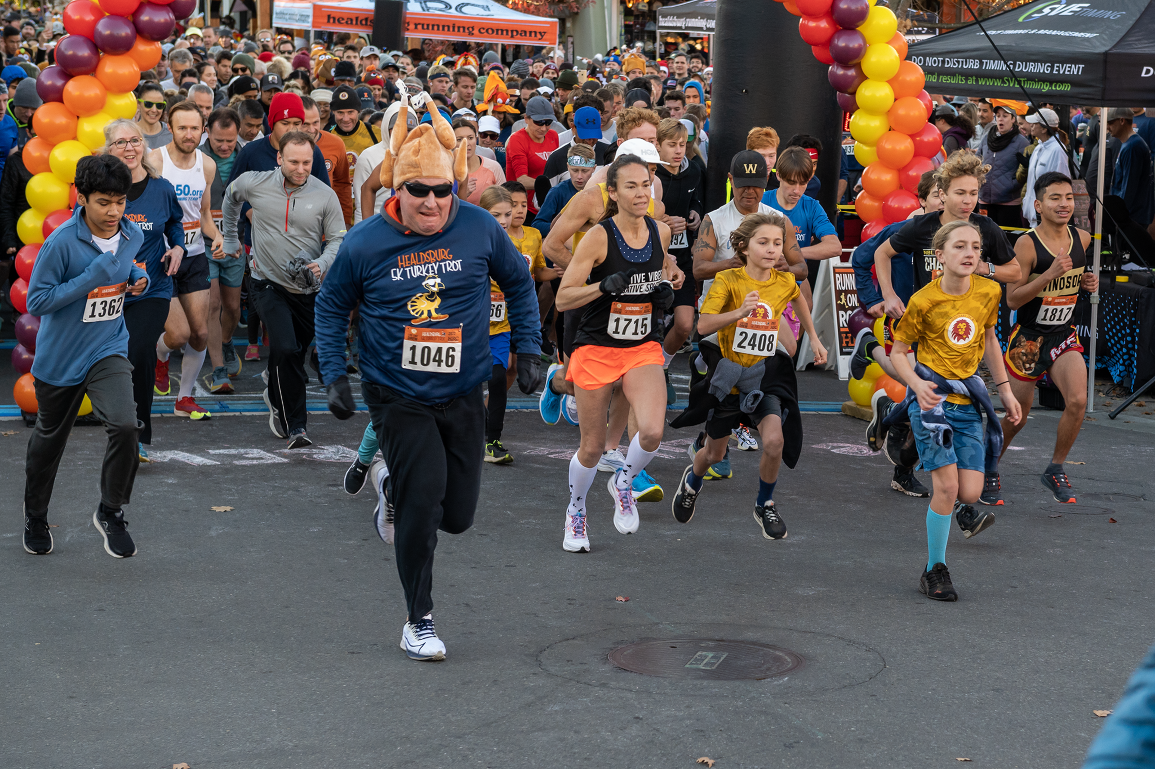 A man wearing a turkey hat leads a pack of runners.