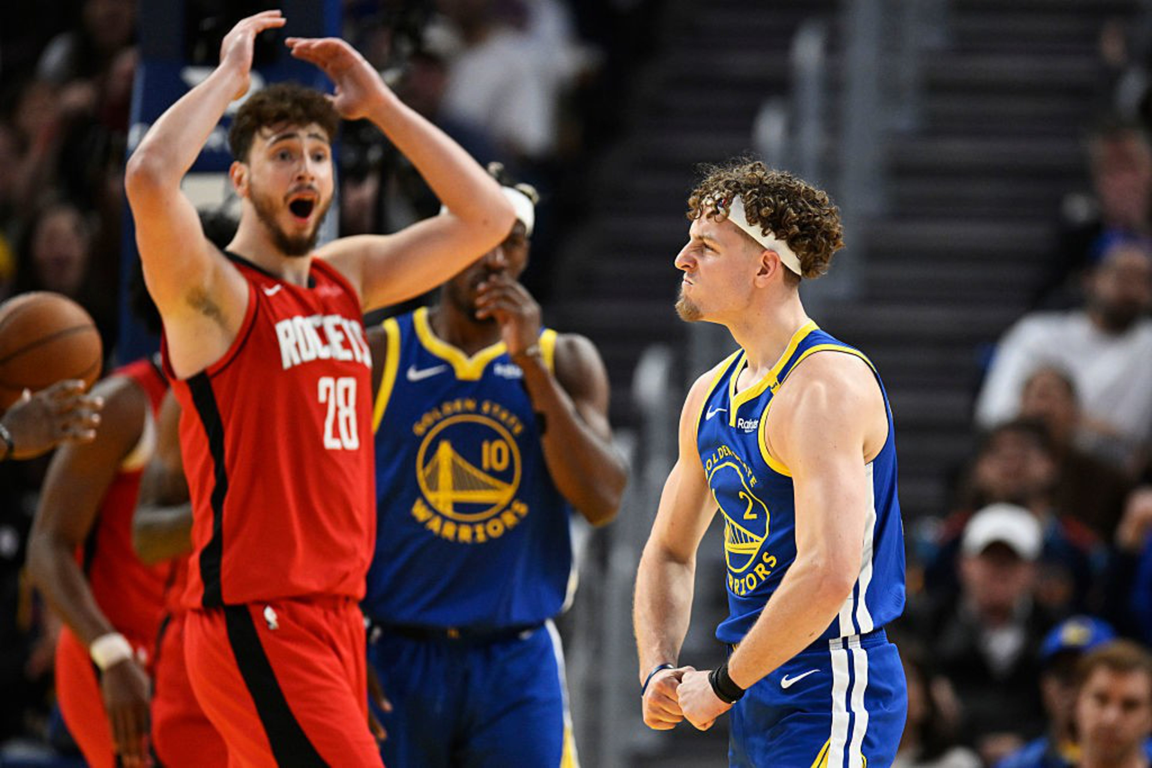 A basketball player in a blue uniform looks determined, clenching fists, while a player in a red uniform appears surprised, with arms raised and mouth open.