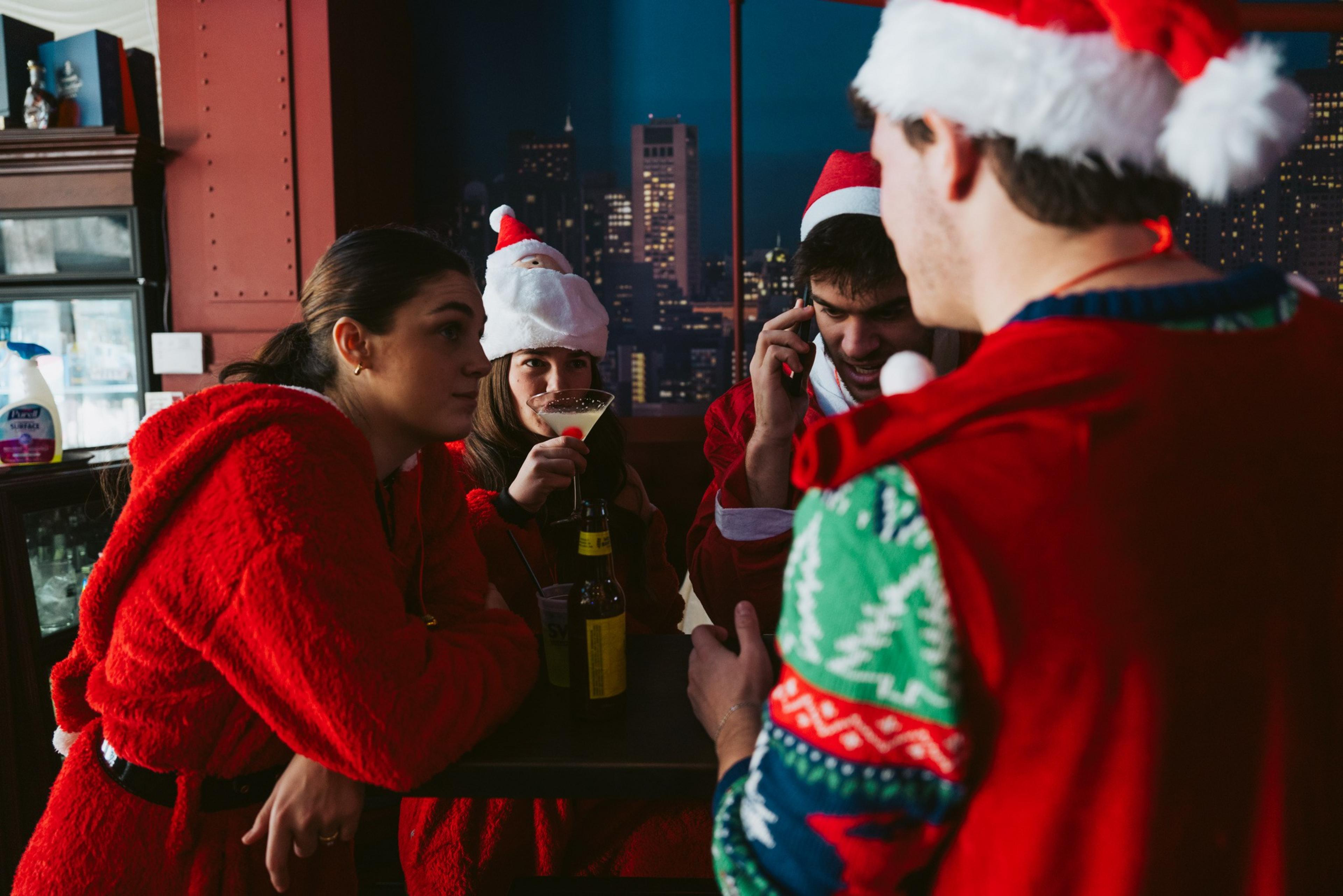 Patrons wearing Santa outfits enjoy drinks at a bar.