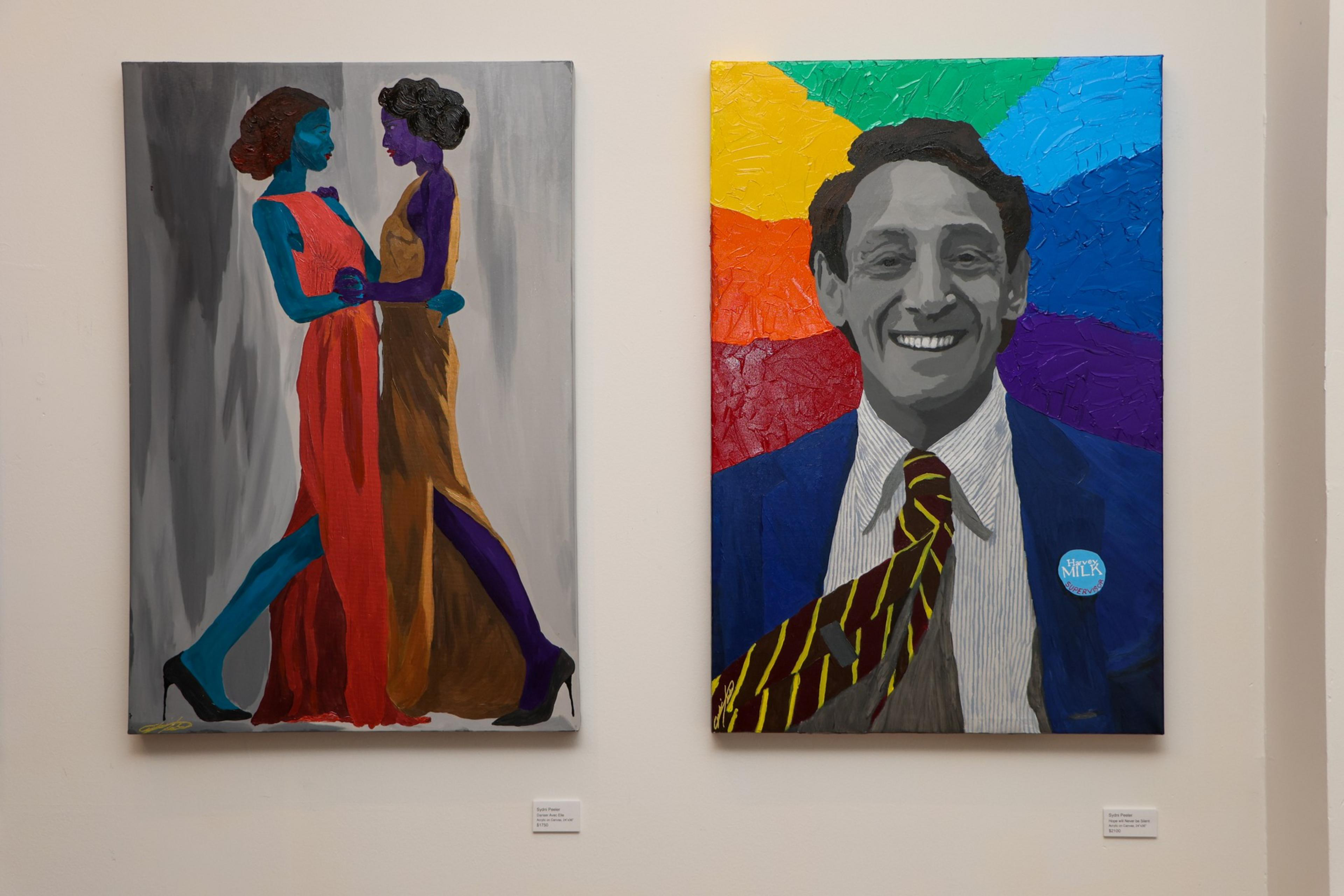 Two vibrant paintings hang side by side; the left depicts two colorful women in long dresses facing each other, the right shows a smiling man in a suit with a rainbow background.