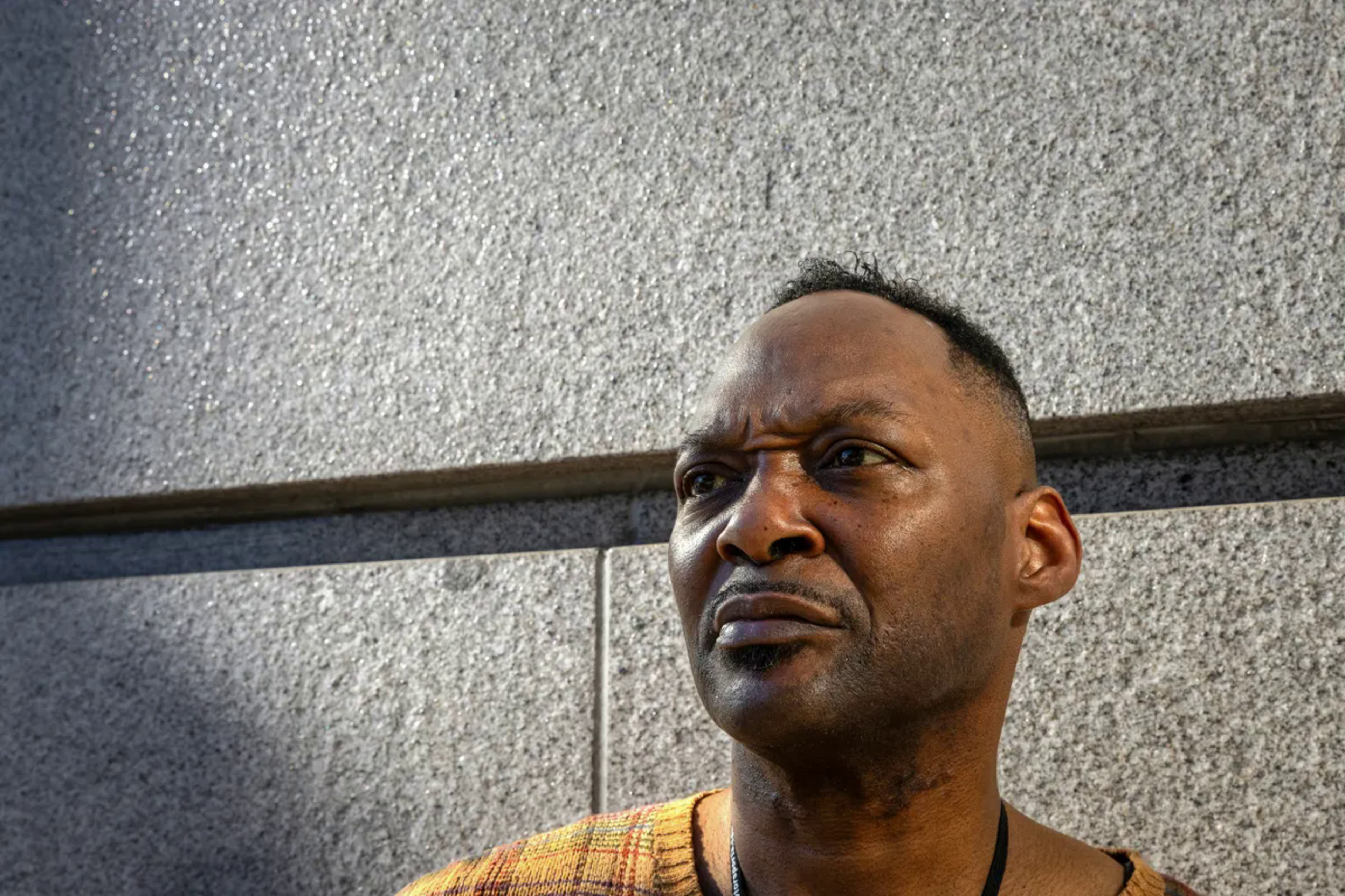Man pictured in front of gray building backdrop