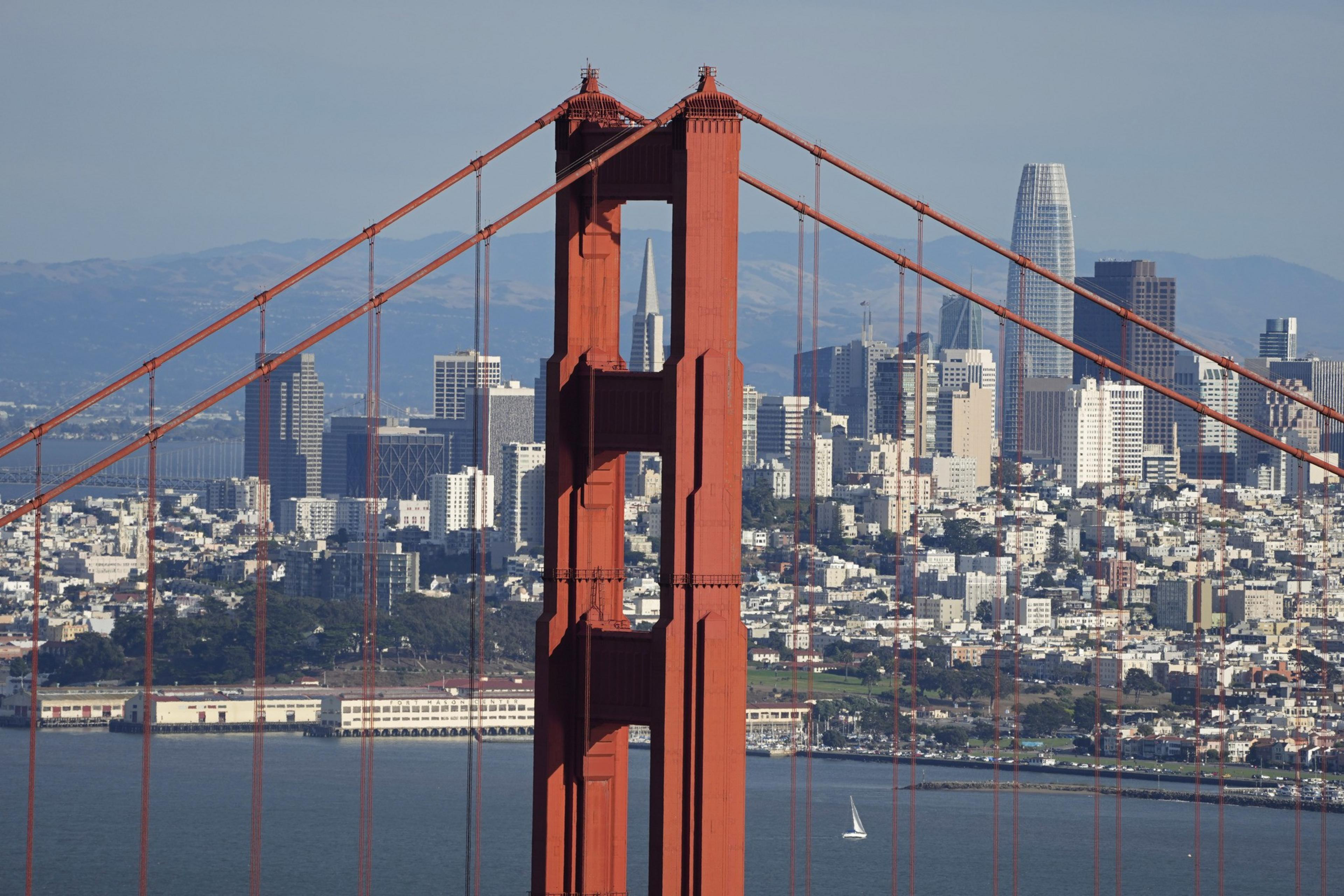 The San Francisco skyline and the San Francisco Bay are seen in the background behind the Golden Gate Bridge.