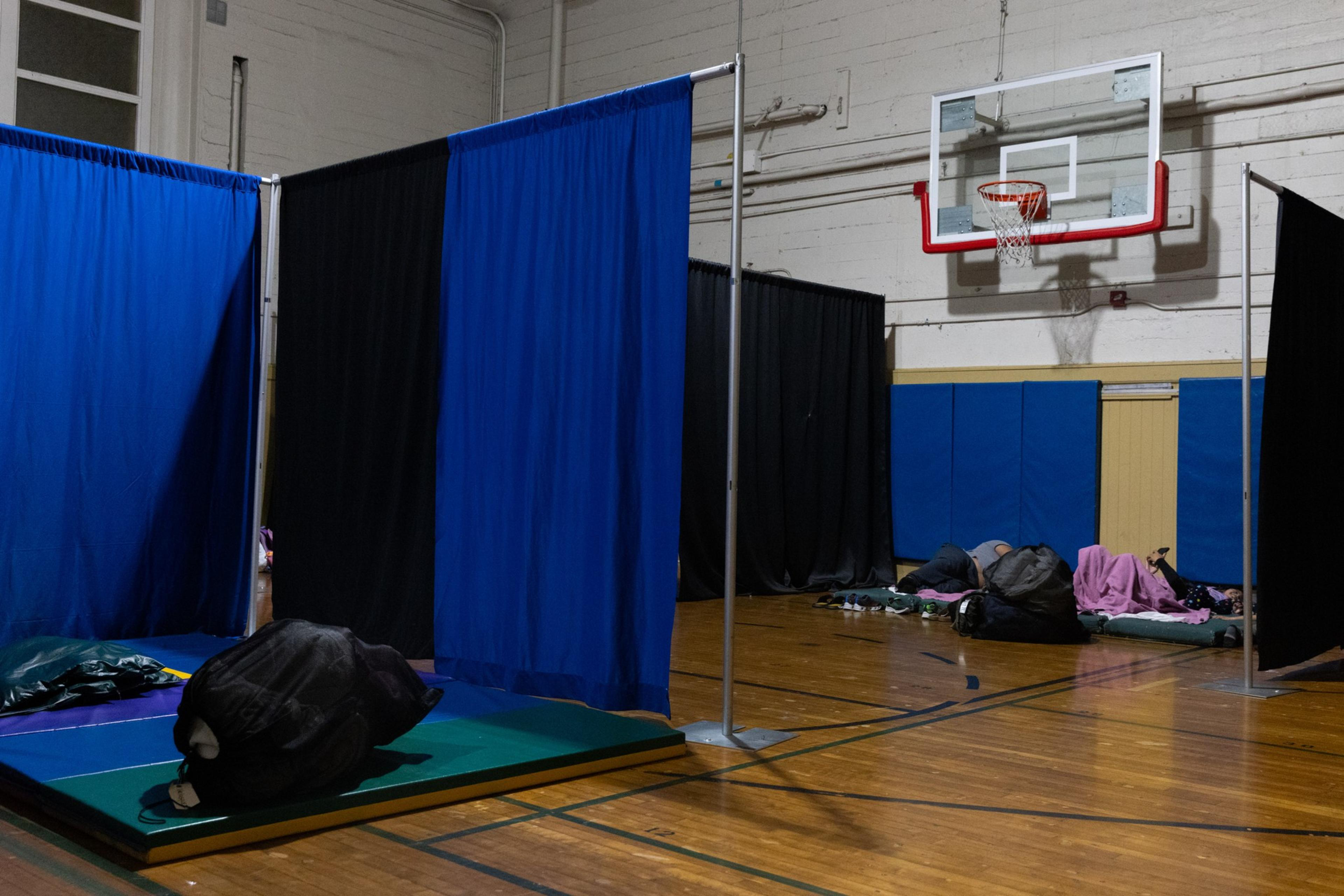 A basketball court divided into sections by blue curtains.