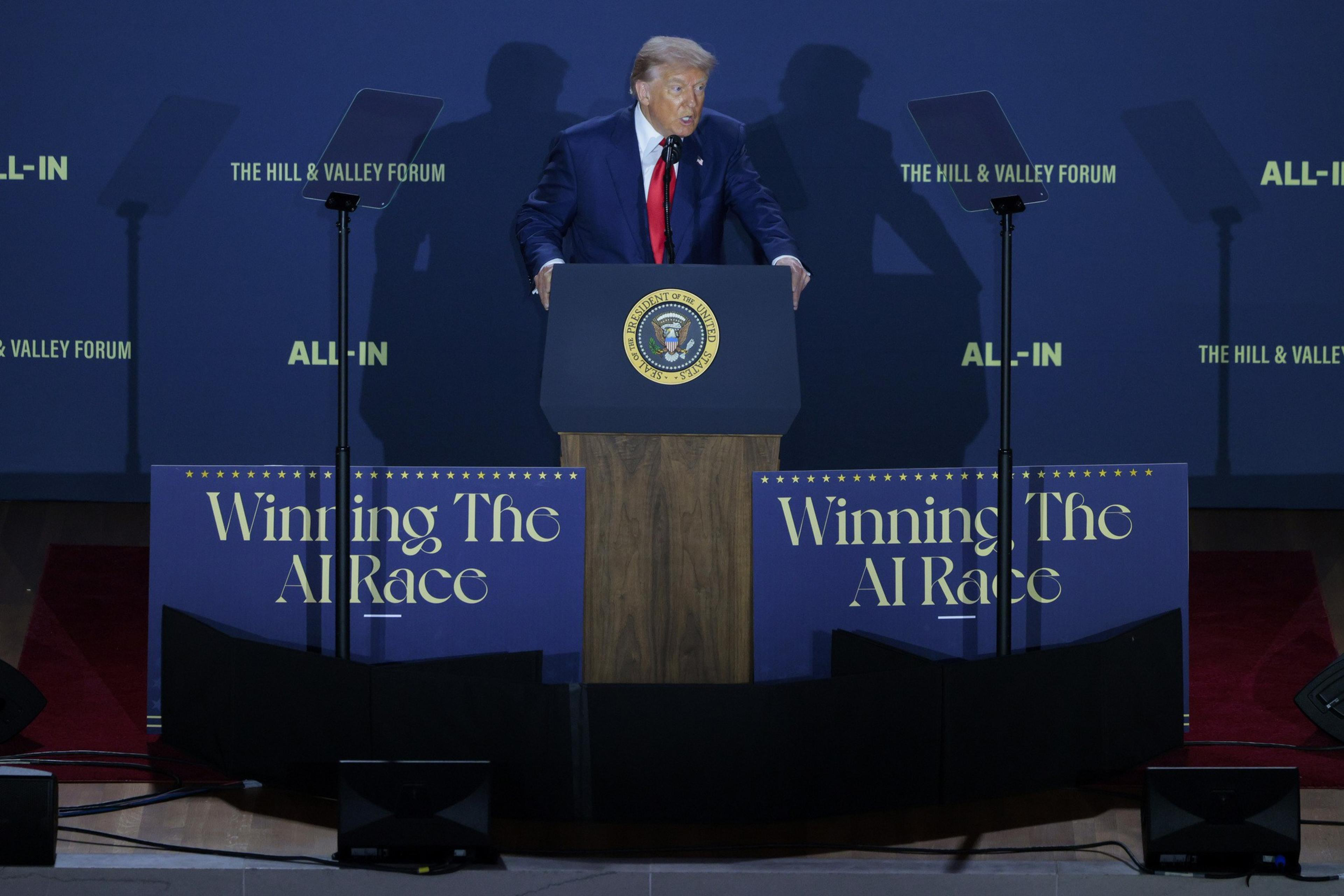 A person stands at a podium featuring the U.S. presidential seal, flanked by signs reading &quot;Winning The AI Race&quot; at an event titled &quot;The Hill &amp; Valley Forum.&quot;