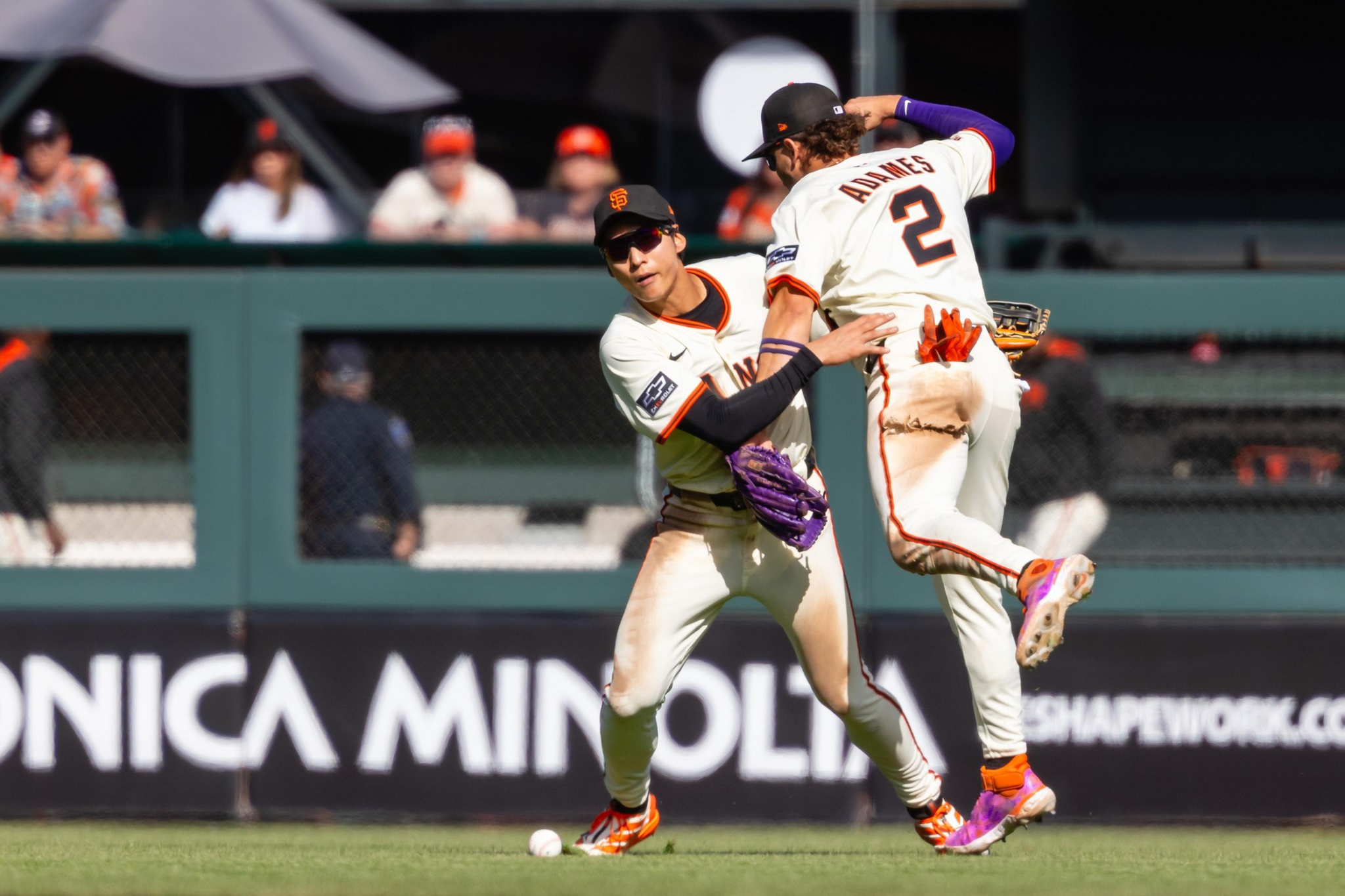 Two baseball players from the San Francisco Giants, one wearing jersey number 2, collide while trying to catch a baseball on the field.