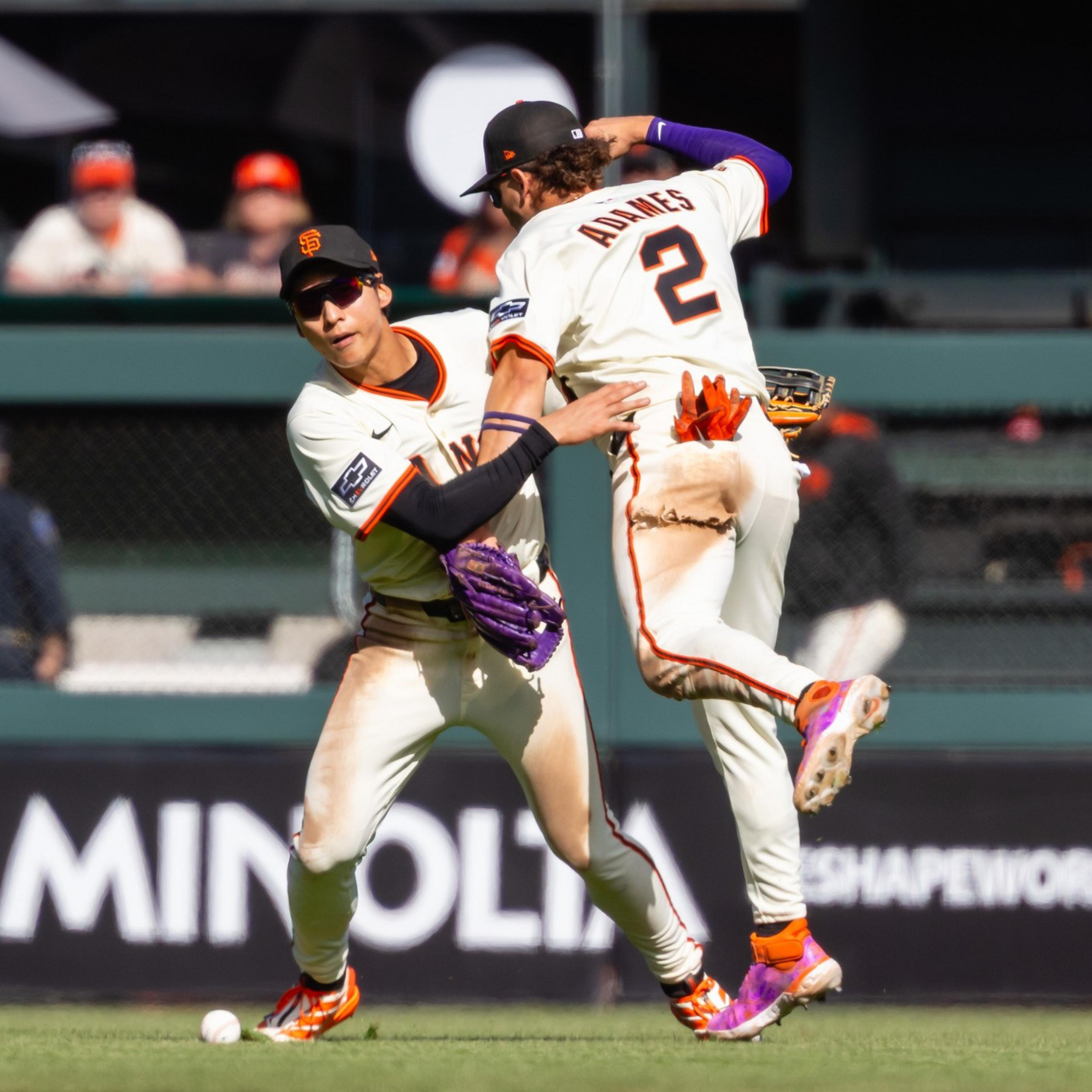Two baseball players from the San Francisco Giants, one wearing jersey number 2, collide while trying to catch a baseball on the field.
