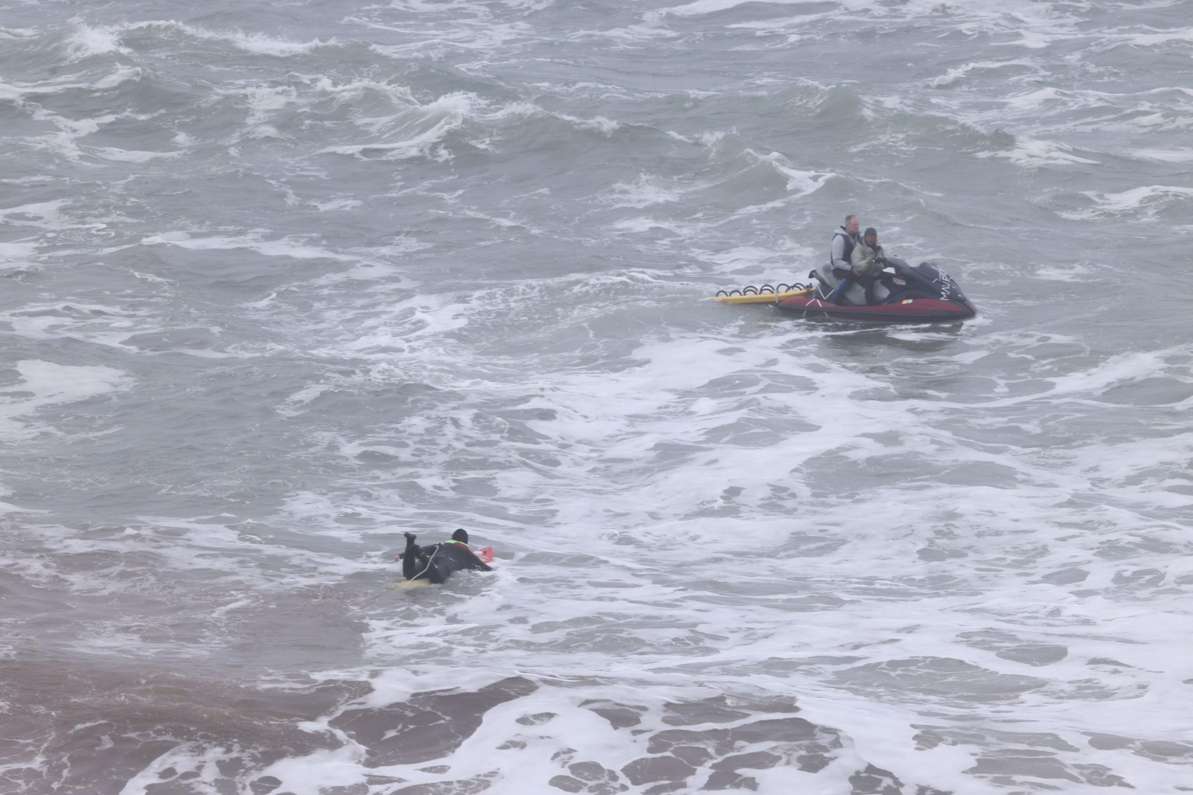 A surfer paddels out to a ski boat to catch some waves. 