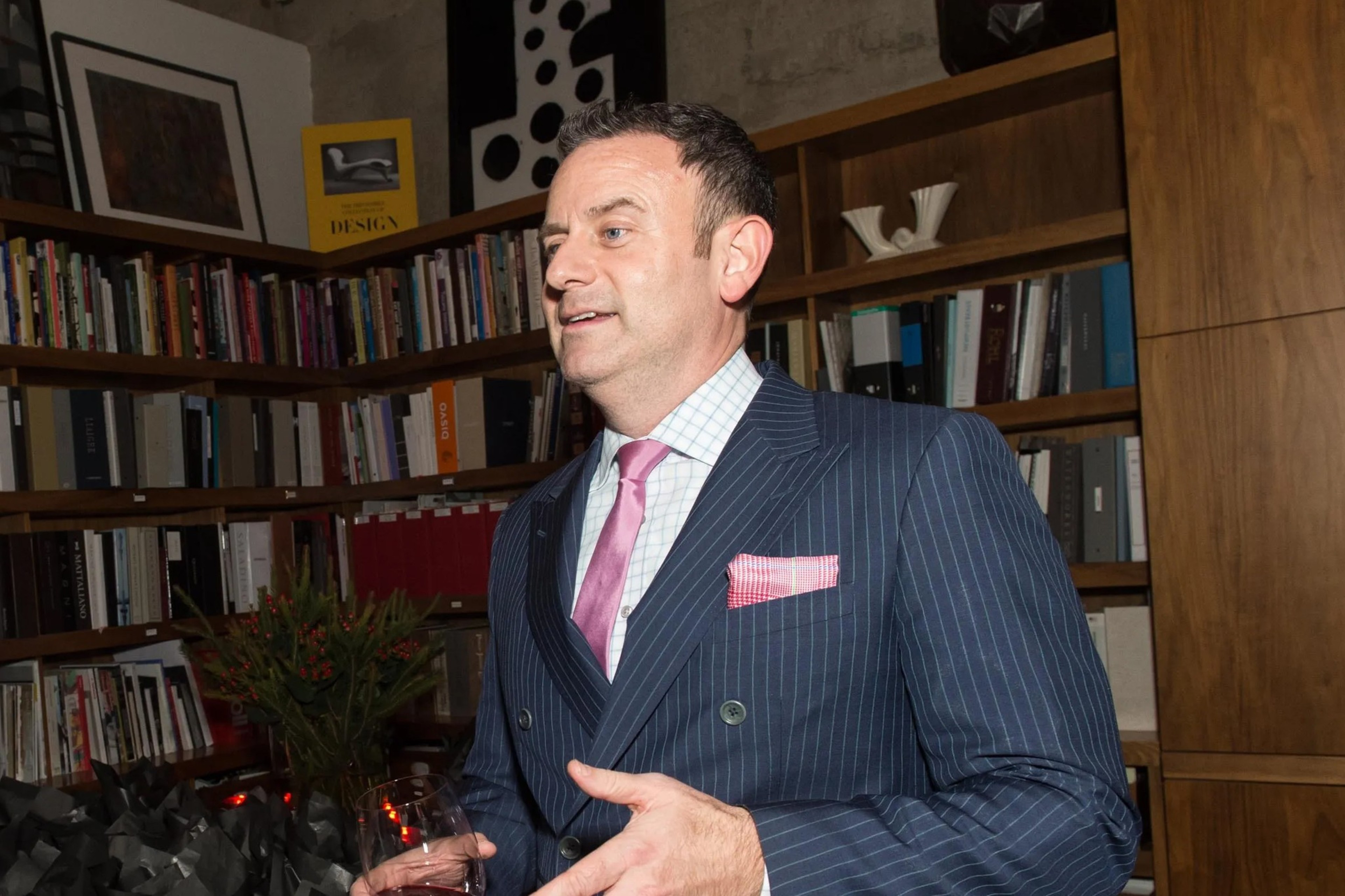 A man in a suit gesticulates while talking.