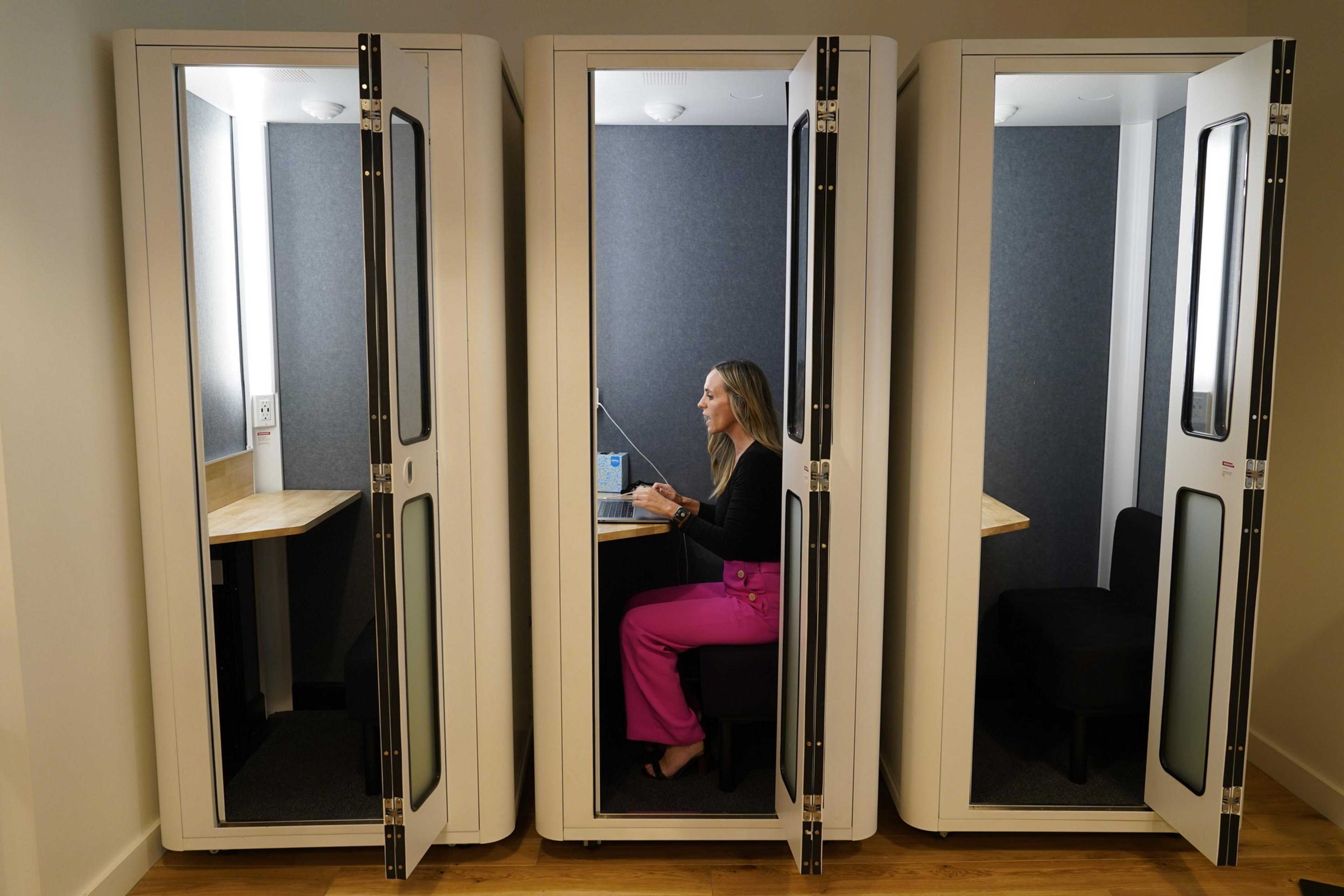 A woman works on a laptop inside a small booth