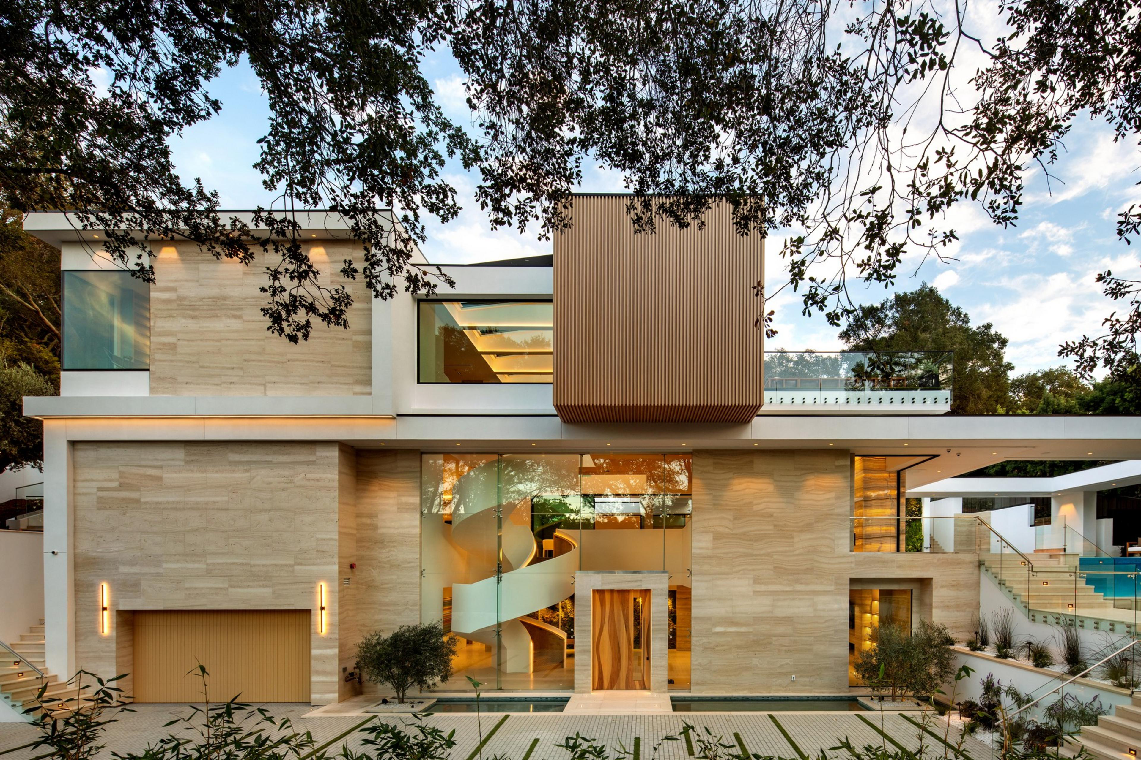 A modern multi-level house features large glass windows, a wooden door, spiral staircase, beige stone façade, and a pool with stair access.