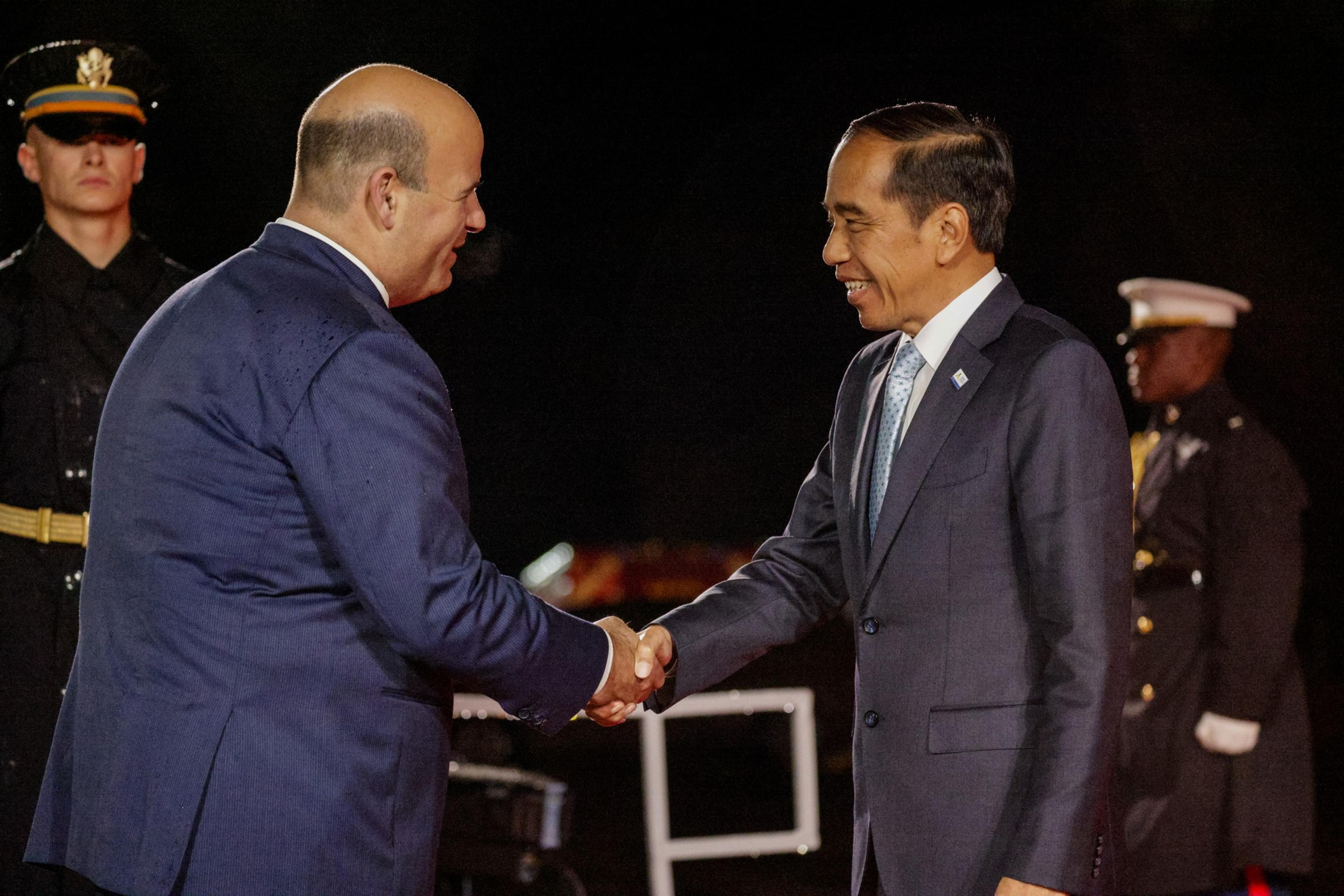 Indonesian President Joko Widodo shakes hands with a state department officials at the Legion of Honor as military servicemen stand guard. 
