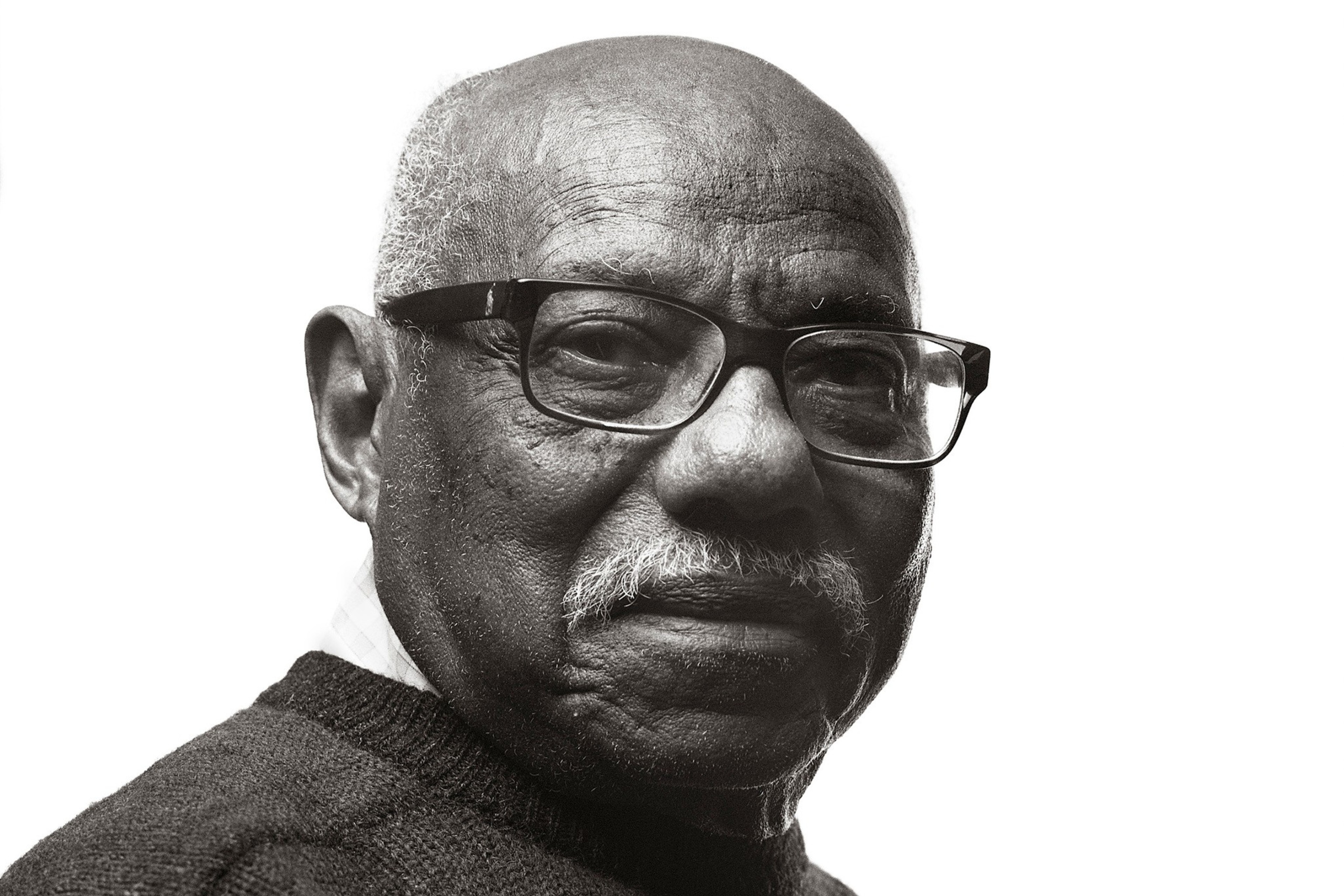 An elder man with glasses, bald on top, and a slight mustache, in a black-and-white portrait.