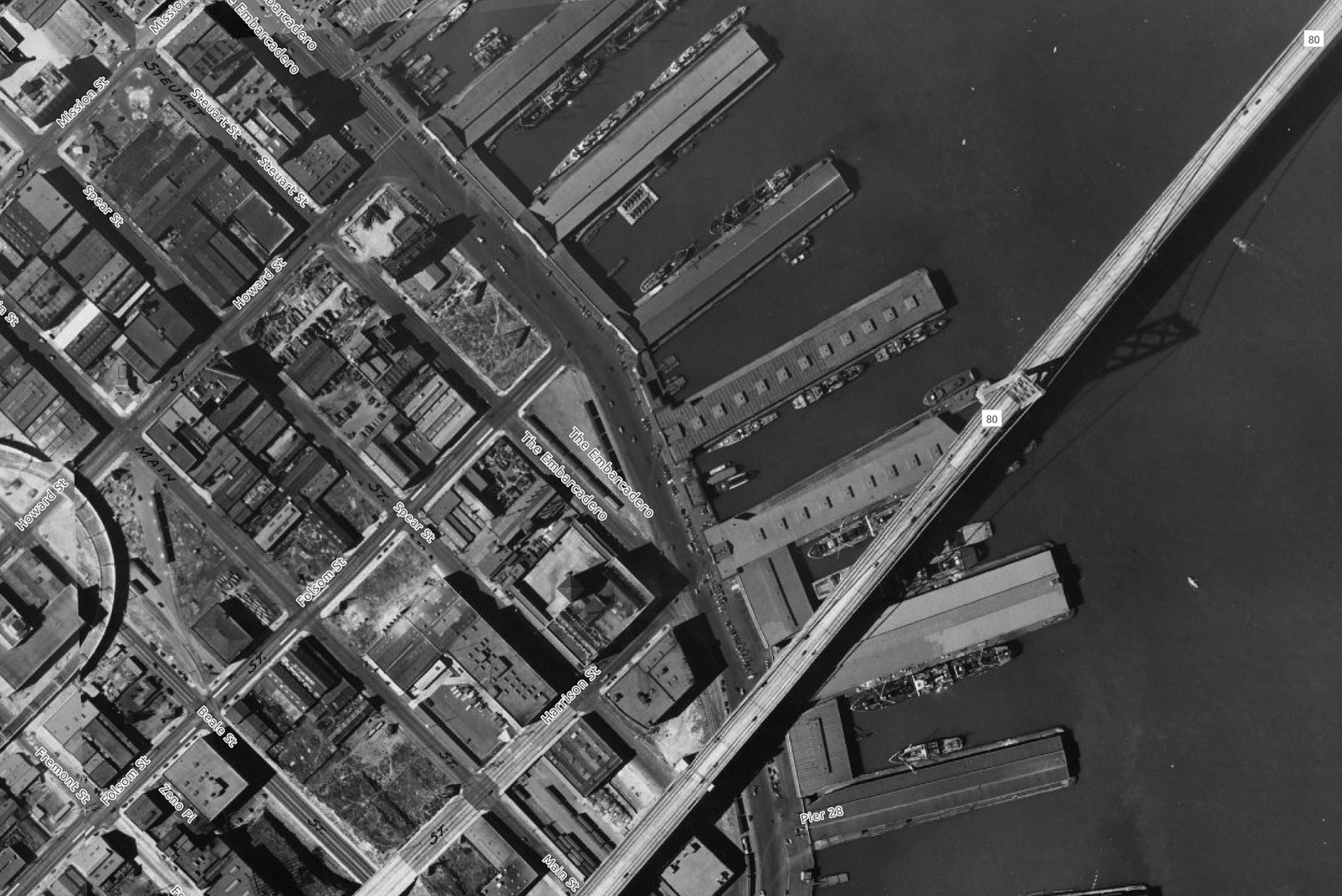 An aerial view of the Oakland-San Francisco Bay Bridge and a number of piers along The Embarcadero in 1938.