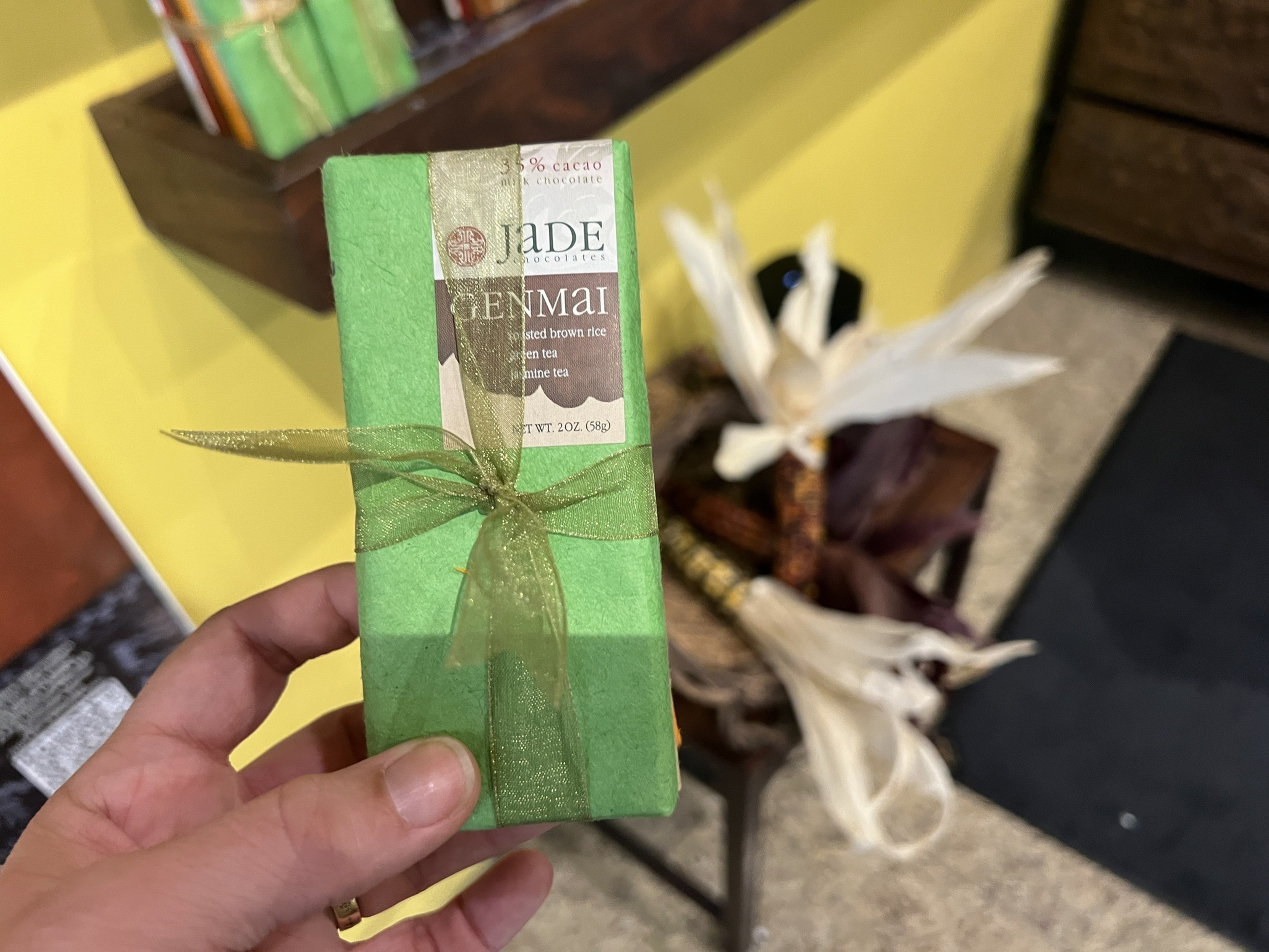 A green-wrapped chocolate bar is tied with a golden ribbon. 