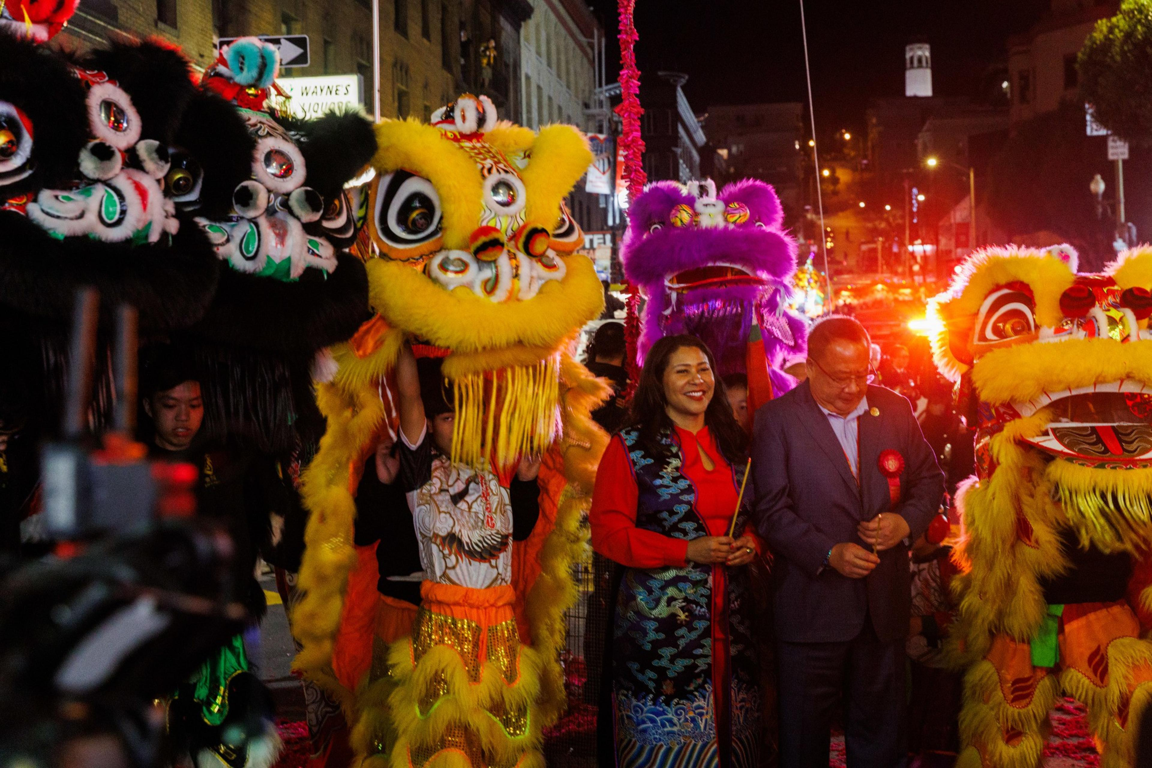 A vibrant street scene with colorful lion dance costumes and two smiling people amid a festive atmosphere.