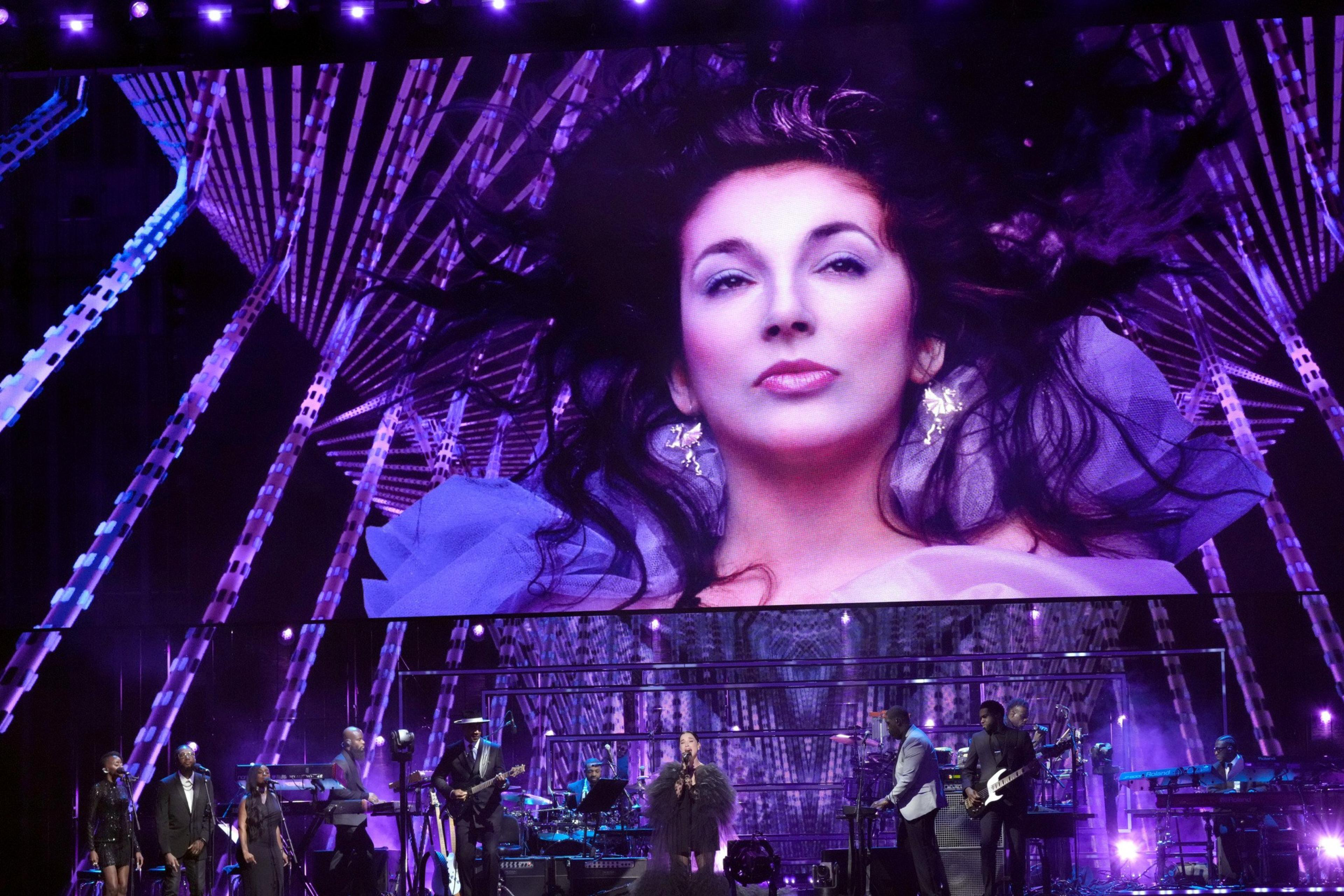St. Vincent seen on a screen projection above her as she plays on stage with her band.