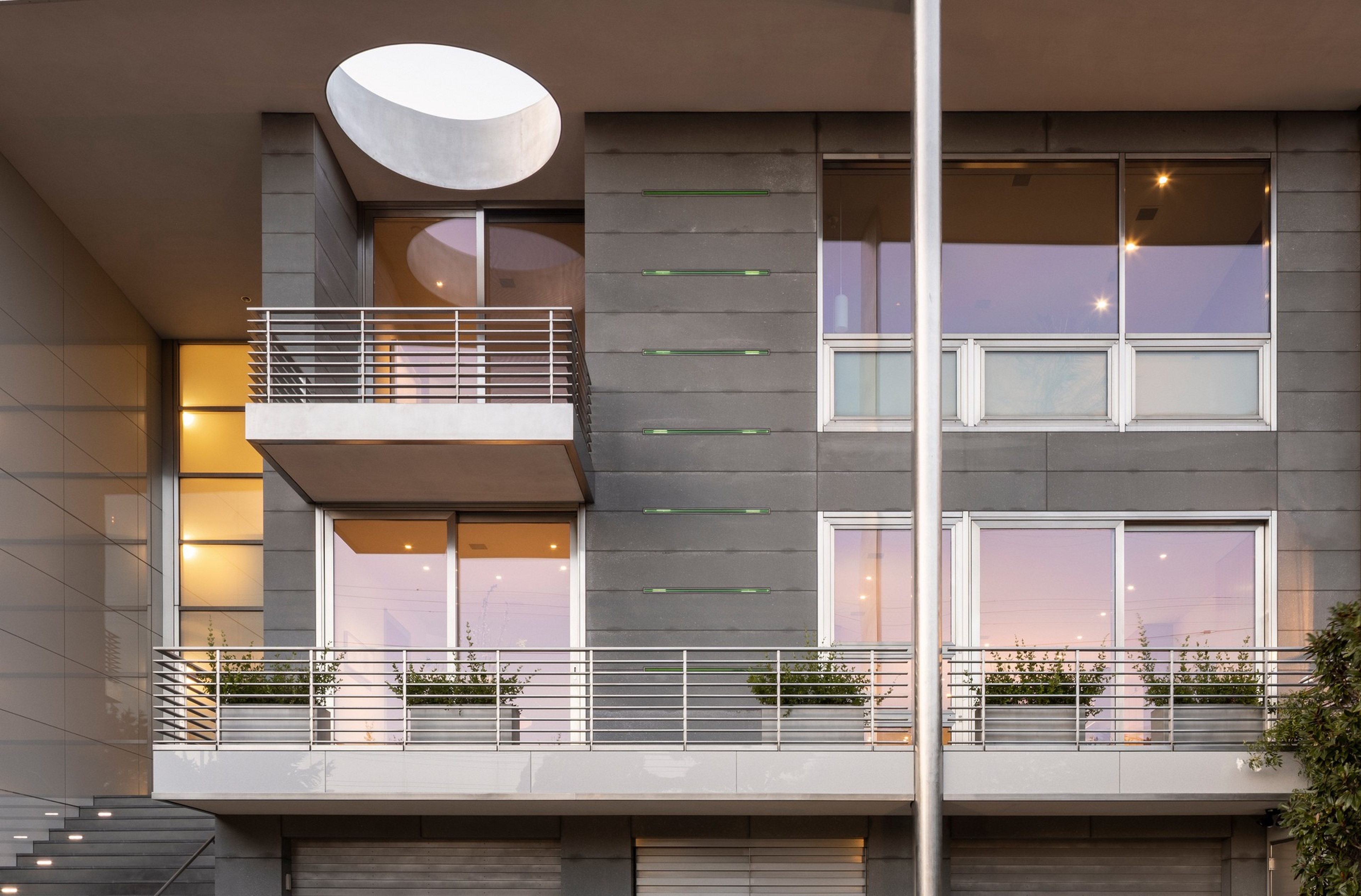 A modern building facade with glass windows, balconies featuring metal ...