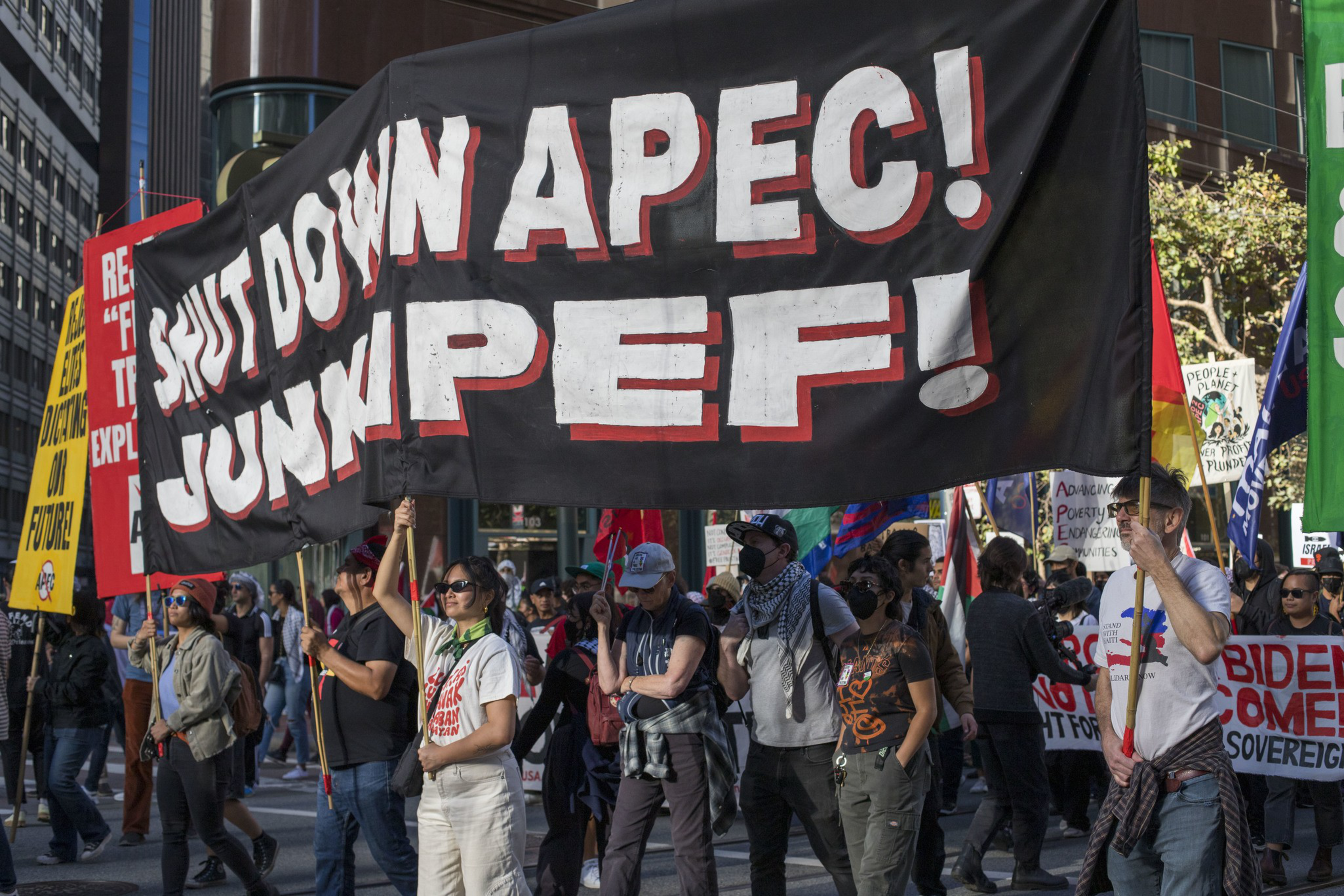 A banner carried by individuals that say &quot;Shut down APEC! Junk IPEF&quot;.