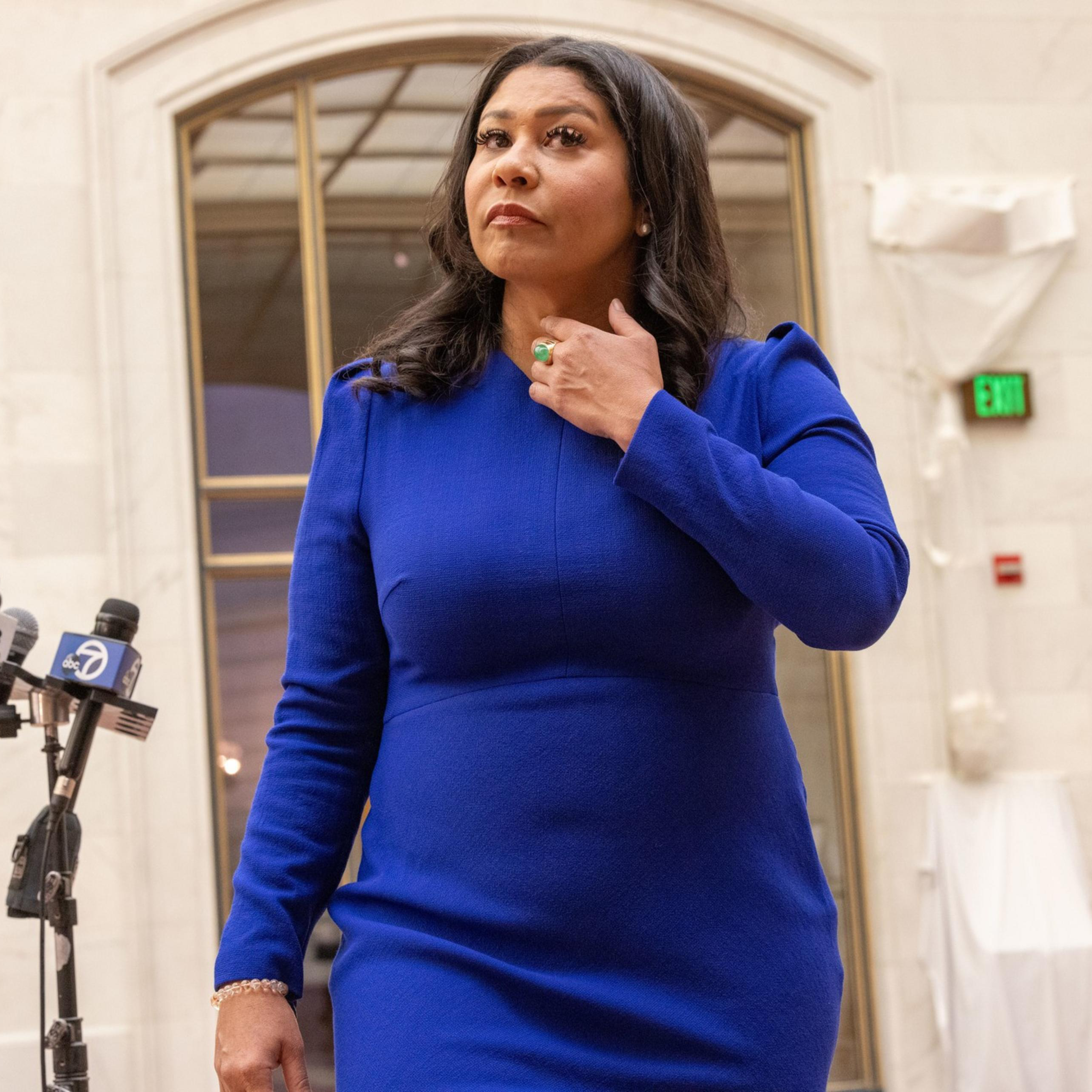 London Breed in blue walks toward the camera.