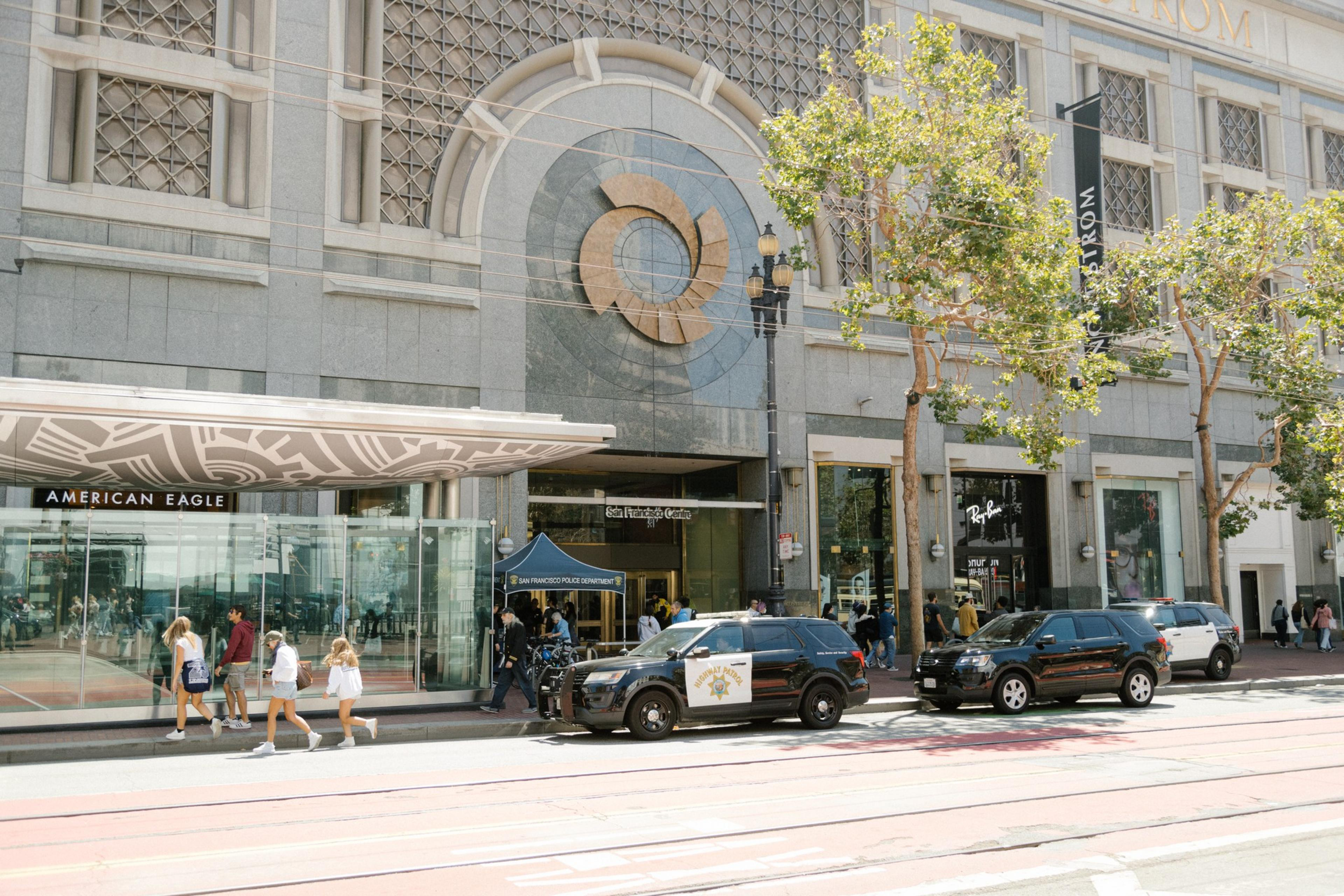 A state highway patrol vehicle is parked outside a large multi-story building on a sunny summer day.