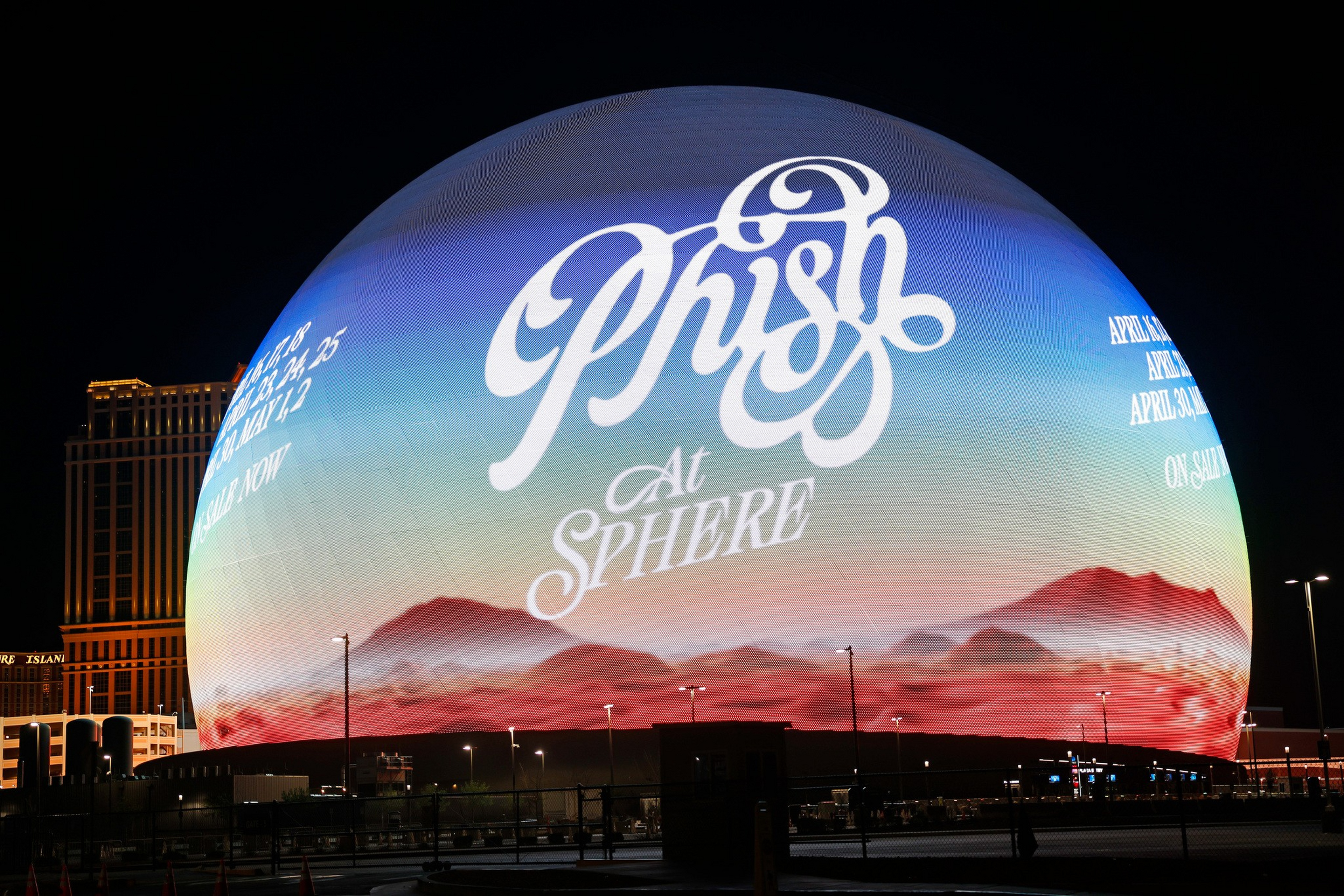A large spherical building lit with a colorful gradient and the word “Phish” in ornate script, along with event dates and “At Sphere” text.