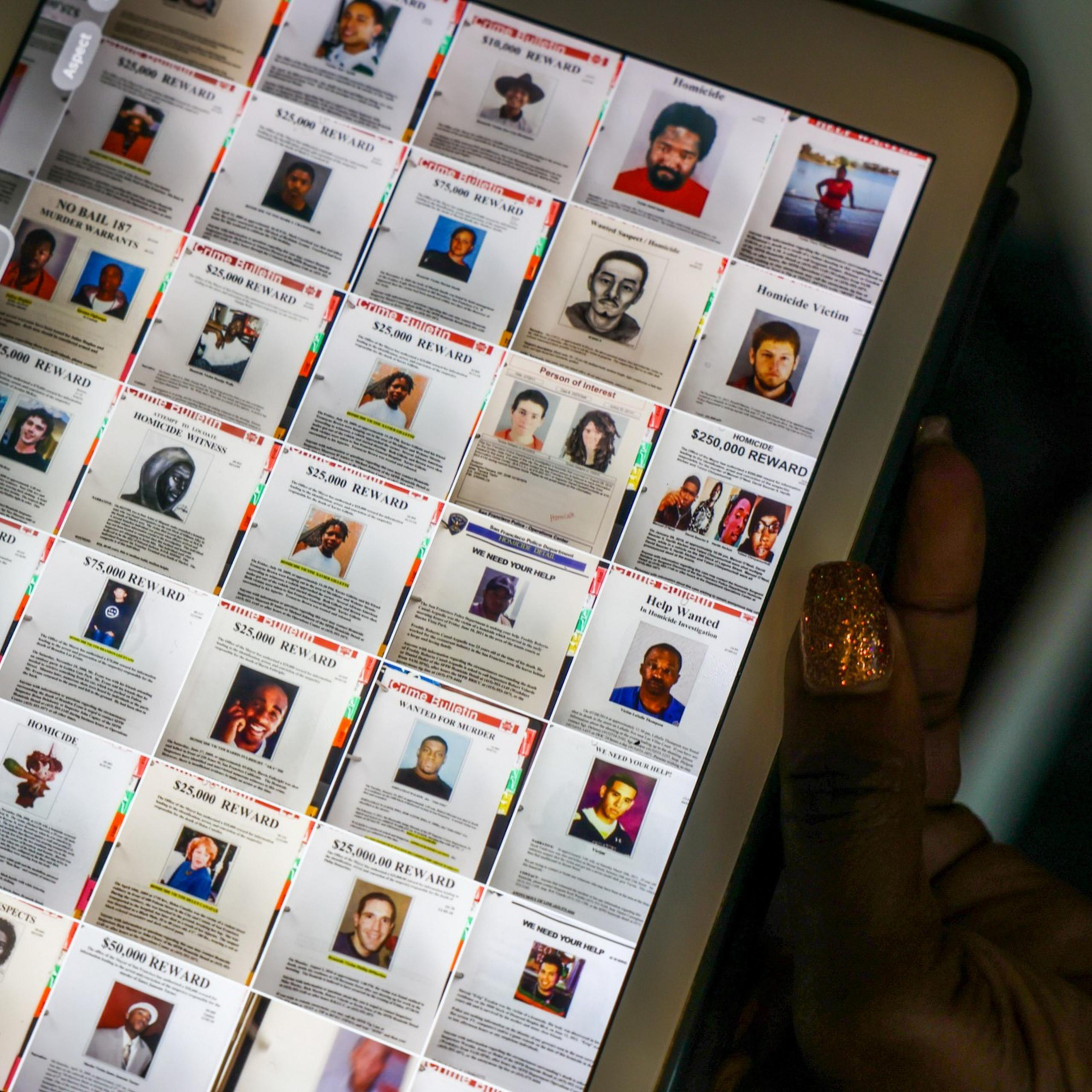 The image shows a computer screen displaying various wanted posters with photos and reward amounts. A hand with glittery nails is holding the screen.