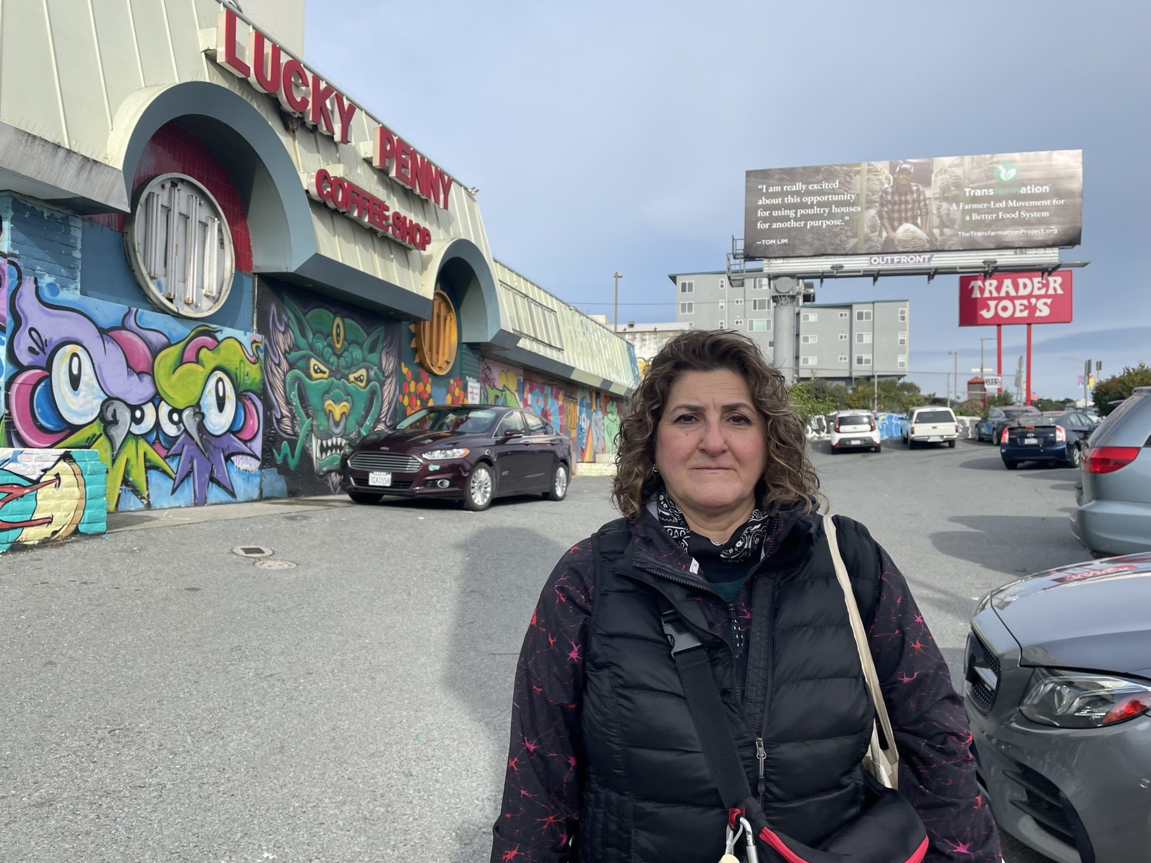A woman stands in a parking lot.