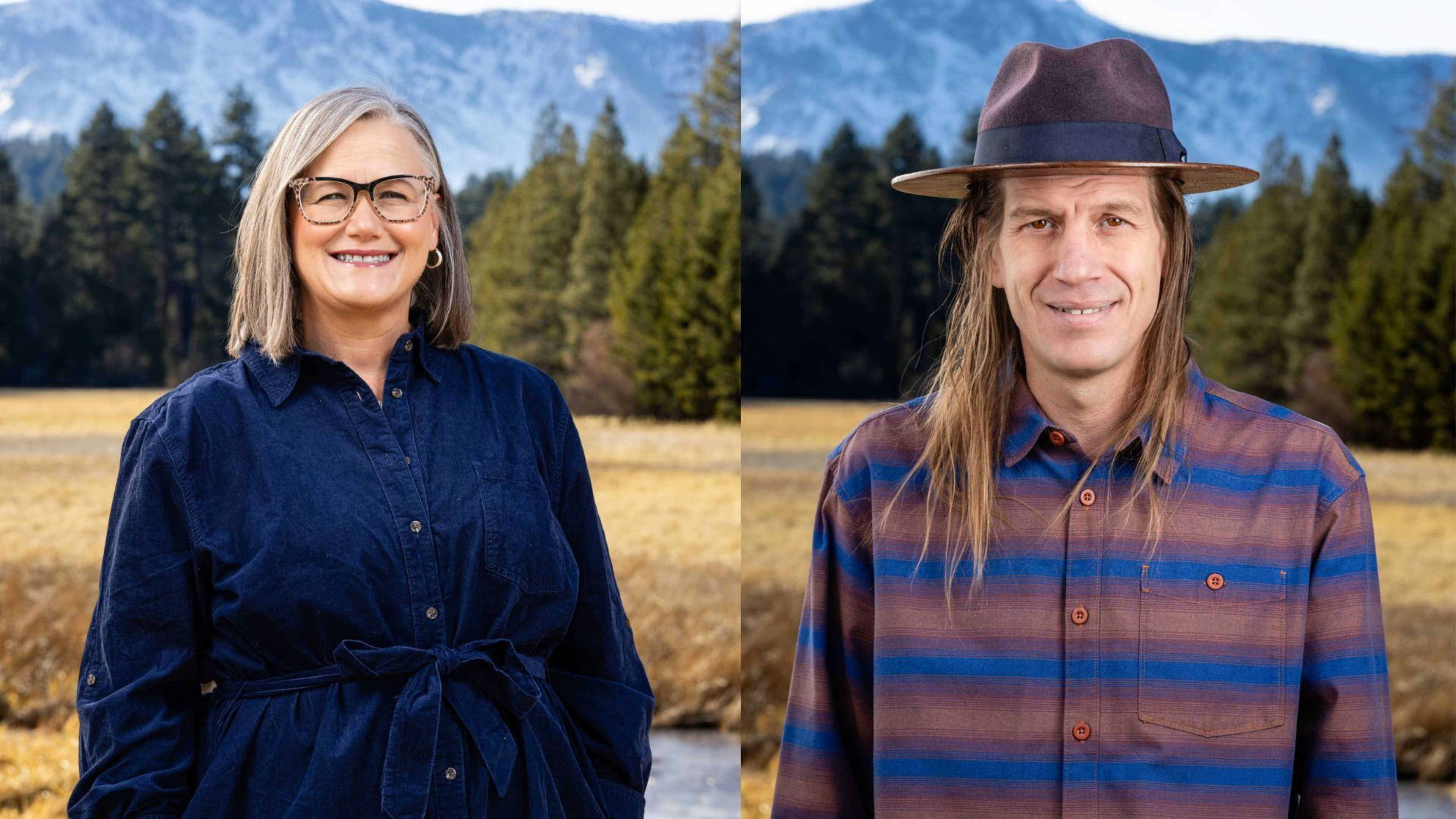 A smiling woman with gray hair and glasses wears a blue dress, standing outdoors next to a man with long hair, a hat, and a striped shirt, with mountains and trees behind them.