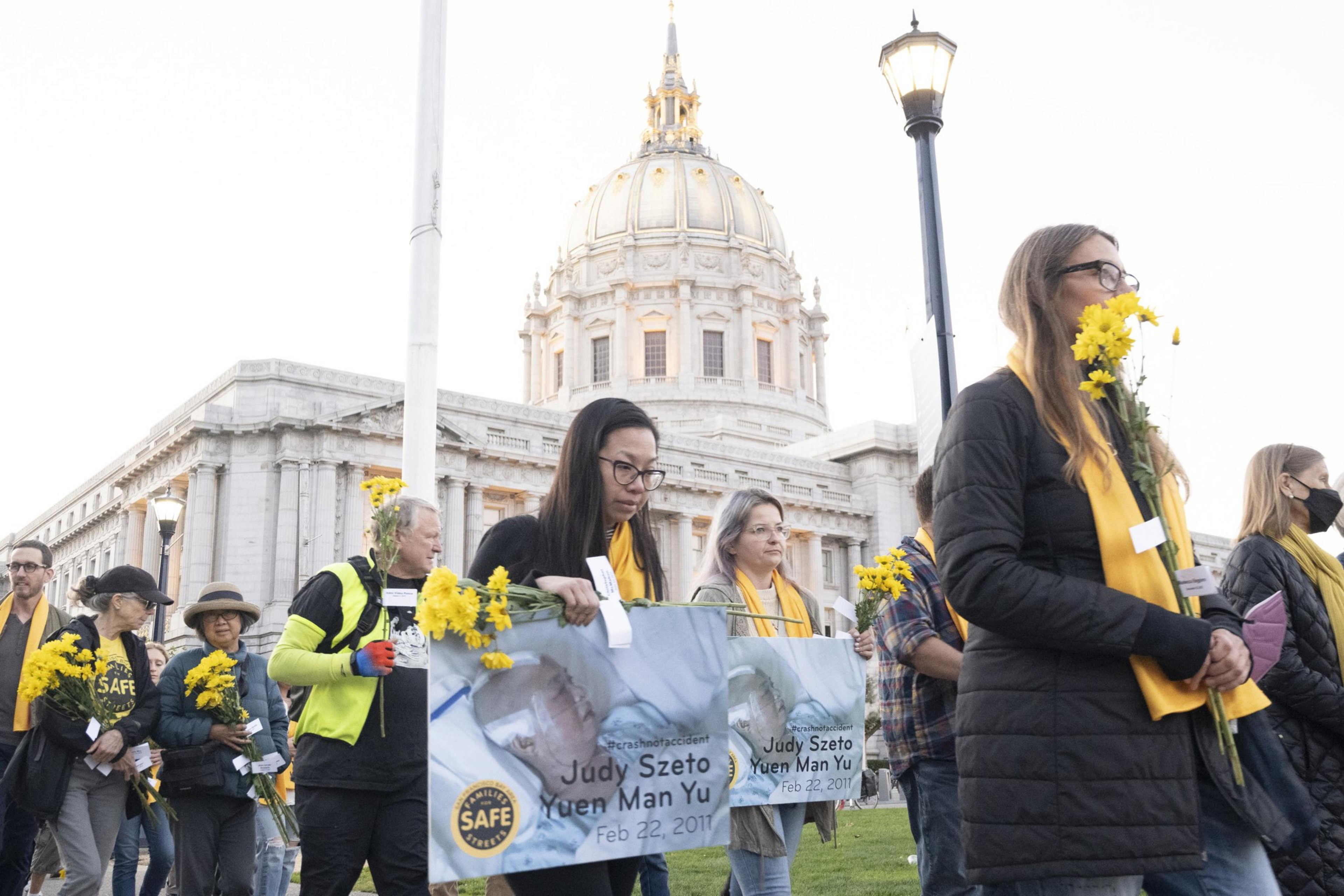 A group of people walk around City Hall in San Francisco during a vigil.