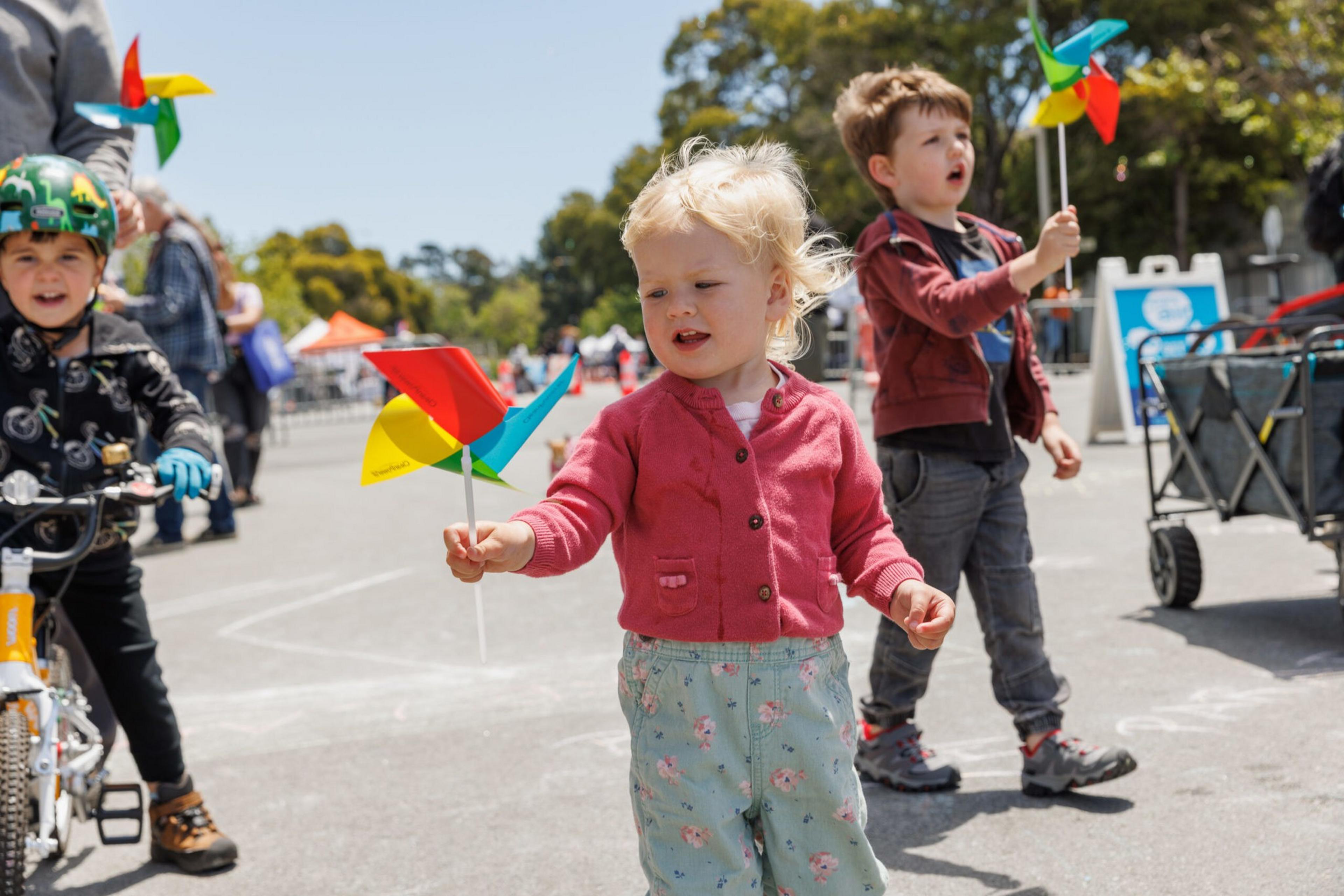 Children with colorful pinwheels at a sunny outdoor event.