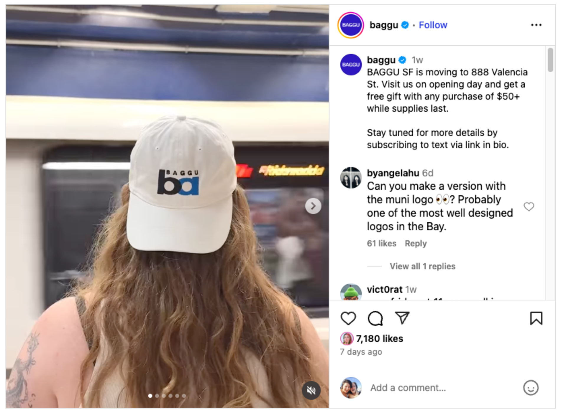 A person with long wavy hair wears a white cap with the "BAGGU" logo while standing in front of a blurred subway train.
