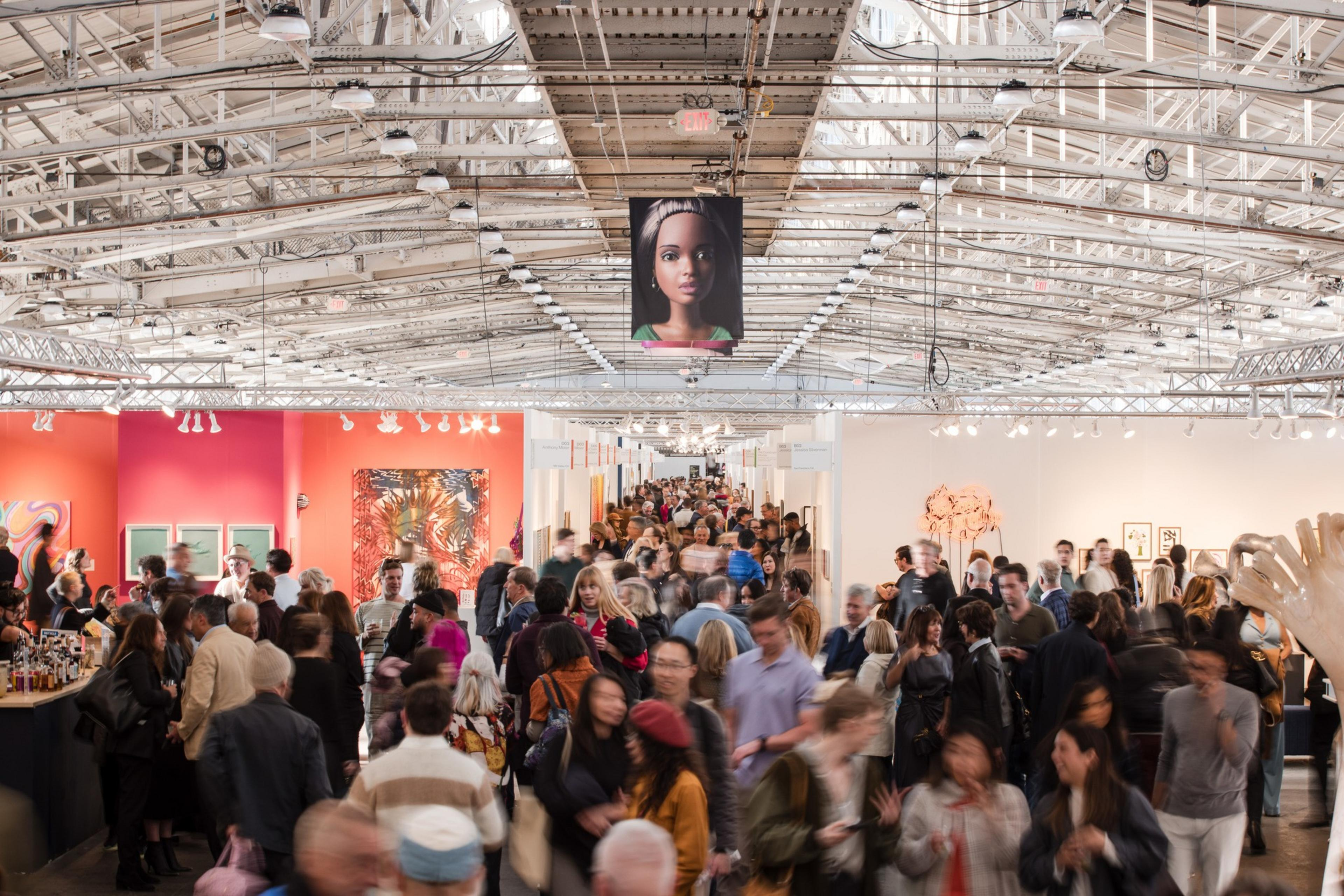 A crowded indoor art gallery or exhibition with people walking and ...